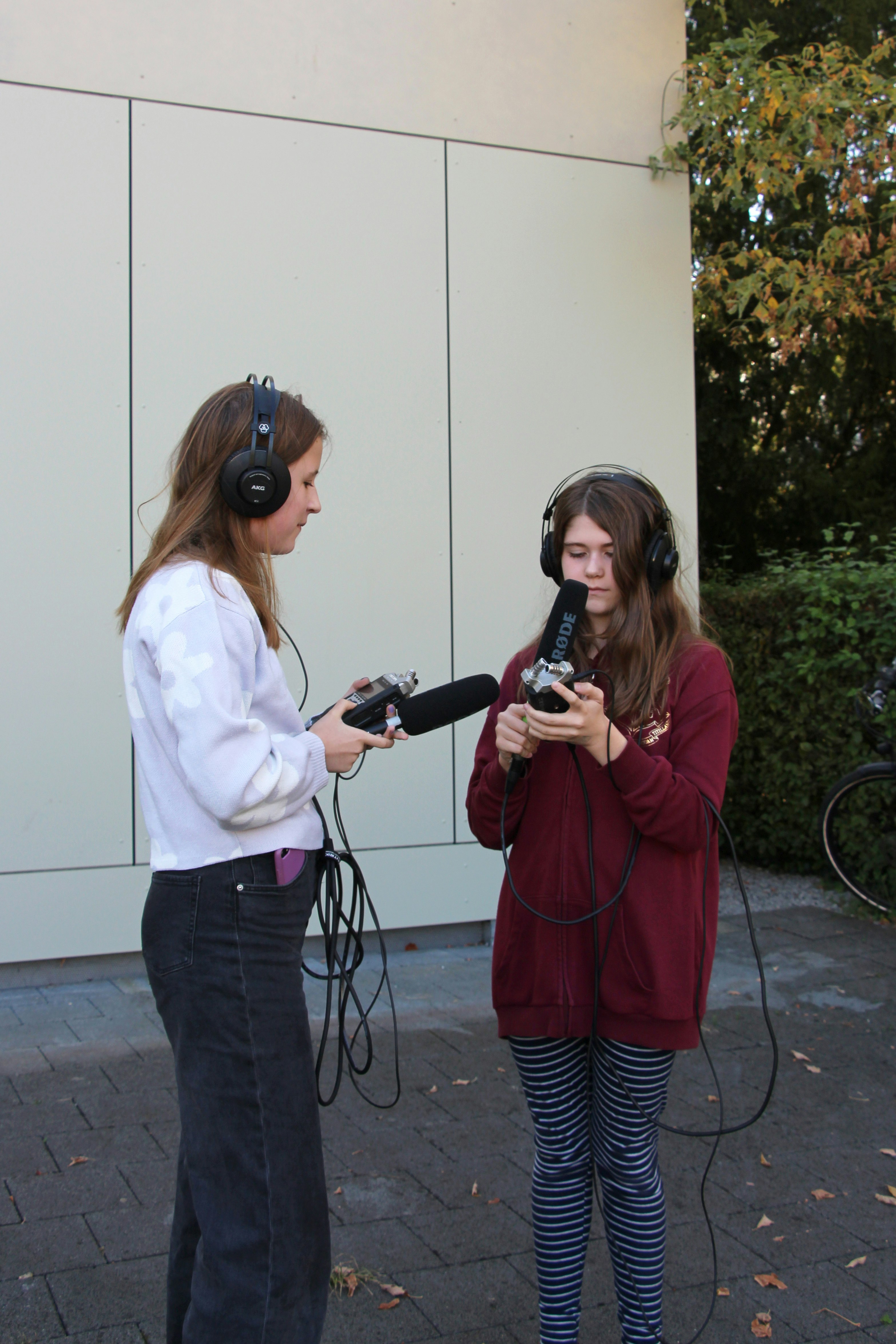 Zwei Mädchen halten Audio-Aufnahmegeräte in den Händen und sprechen ins Mikrofon.