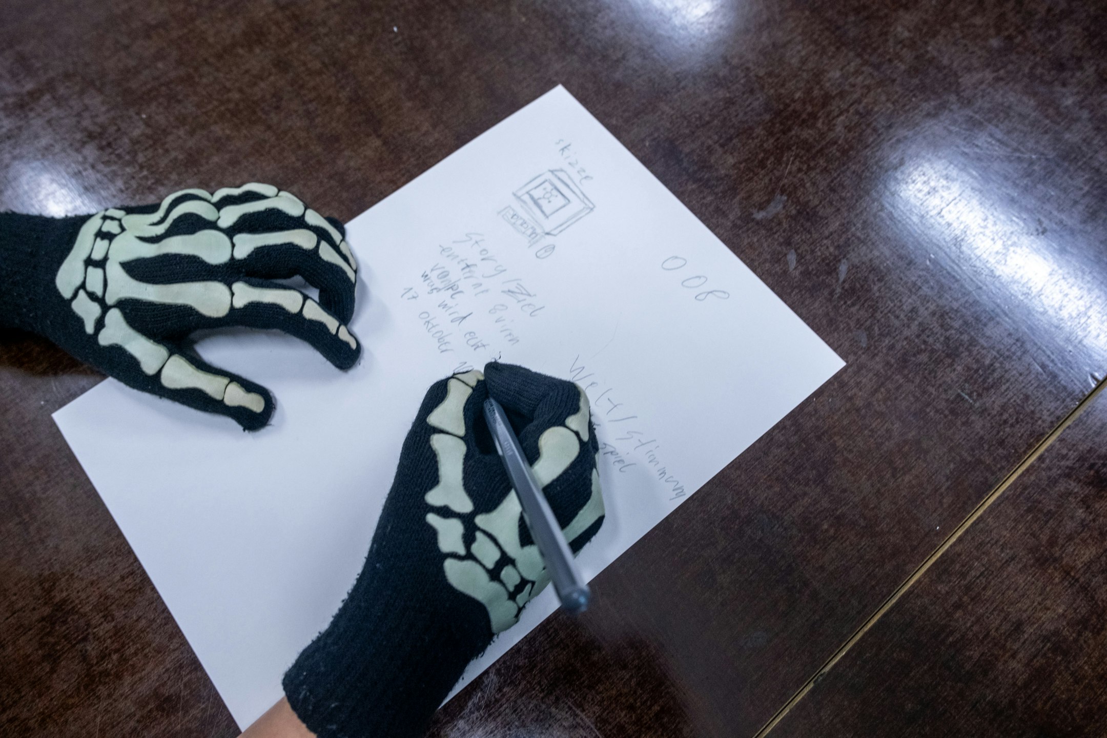 Hände mit Handschuhen mit Skelett am Schreiben