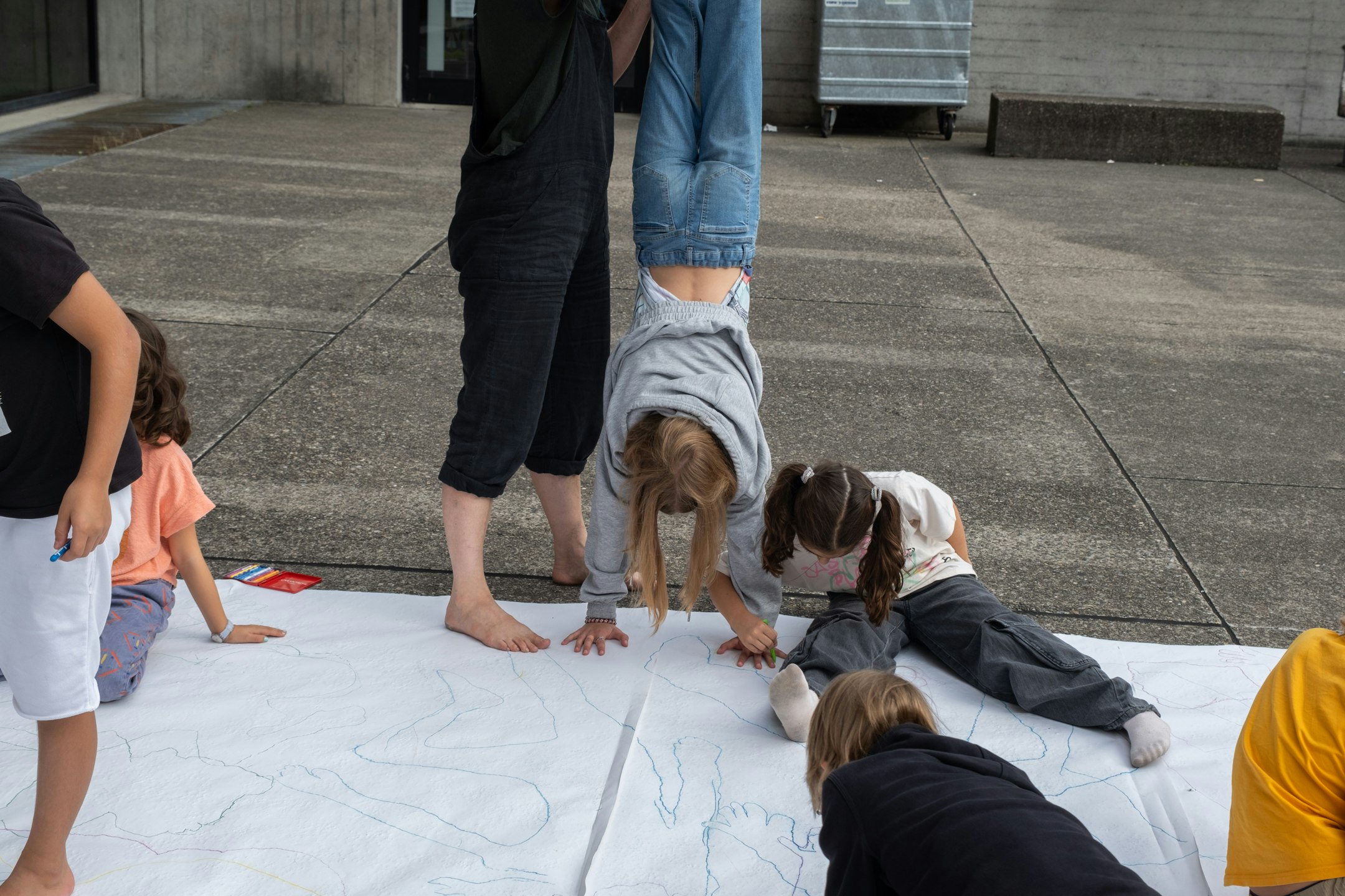 Kinder auf dem Pausenhof am Körperformen Zeichnen auf grossem Papier am Boden liegend
