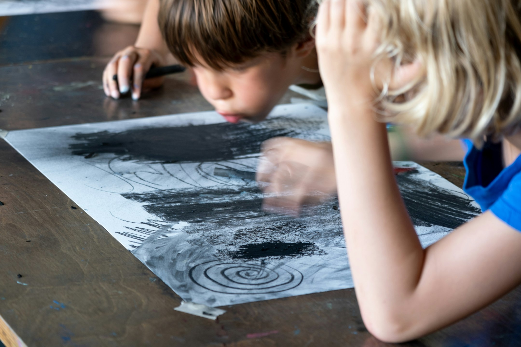 Kohlezeichnung, zwei Kinder  Zeichnen, eines pustet die Kohle vom Papier