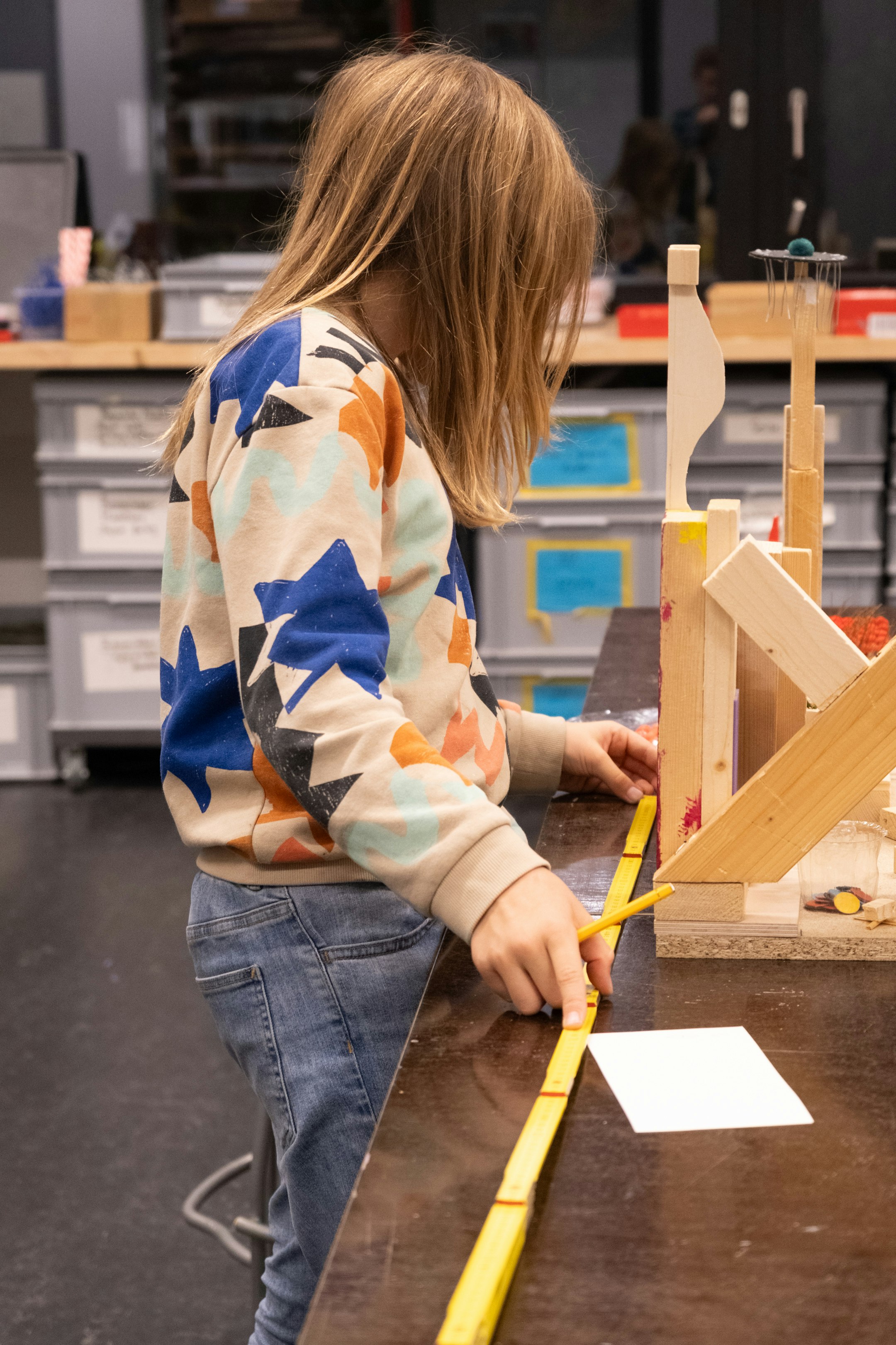Kind am Ausmessen, Figur aus Holz auf der rechten Seite