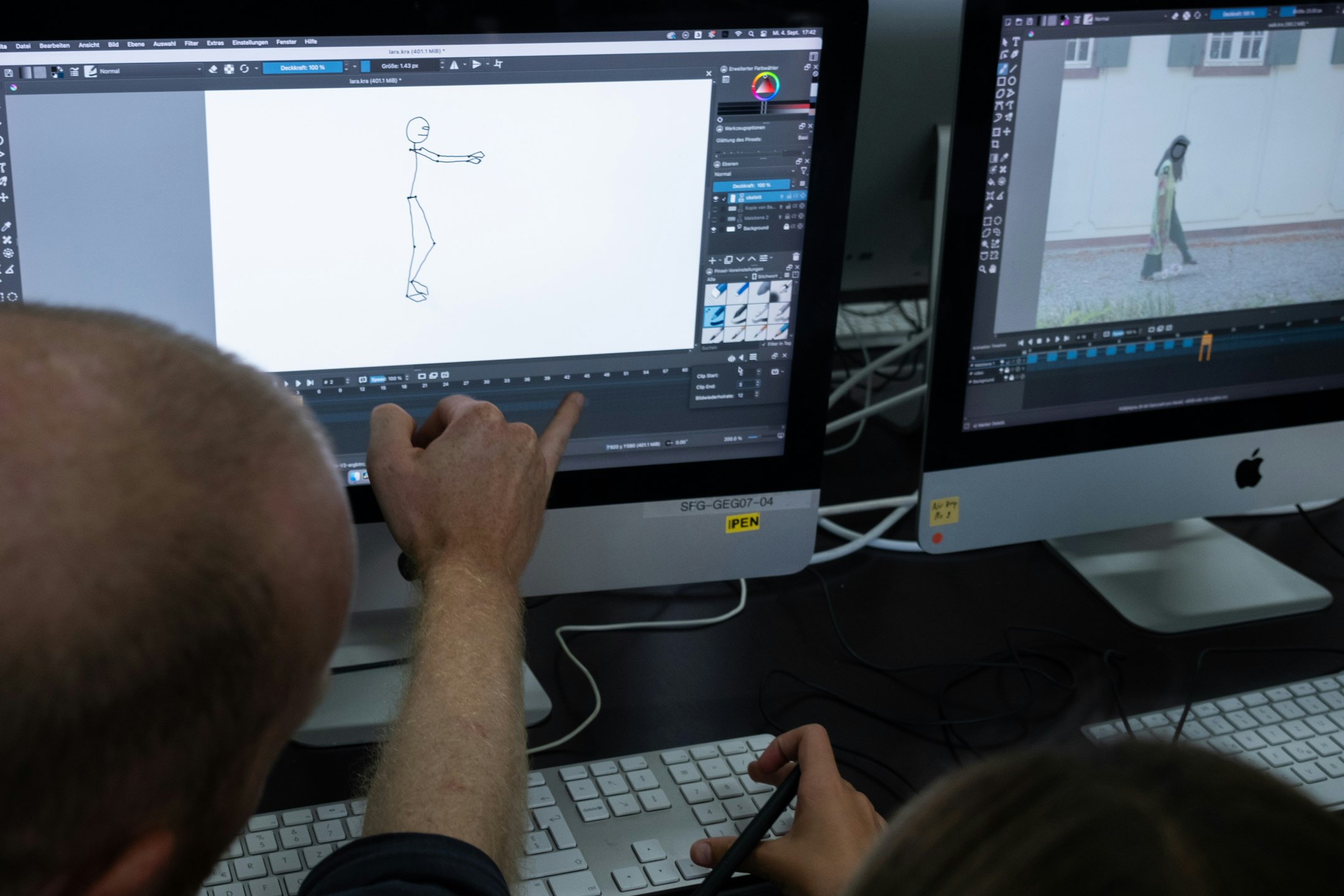 Bildschirme, Unterrichtende Person und Kind von hinten zu sehen