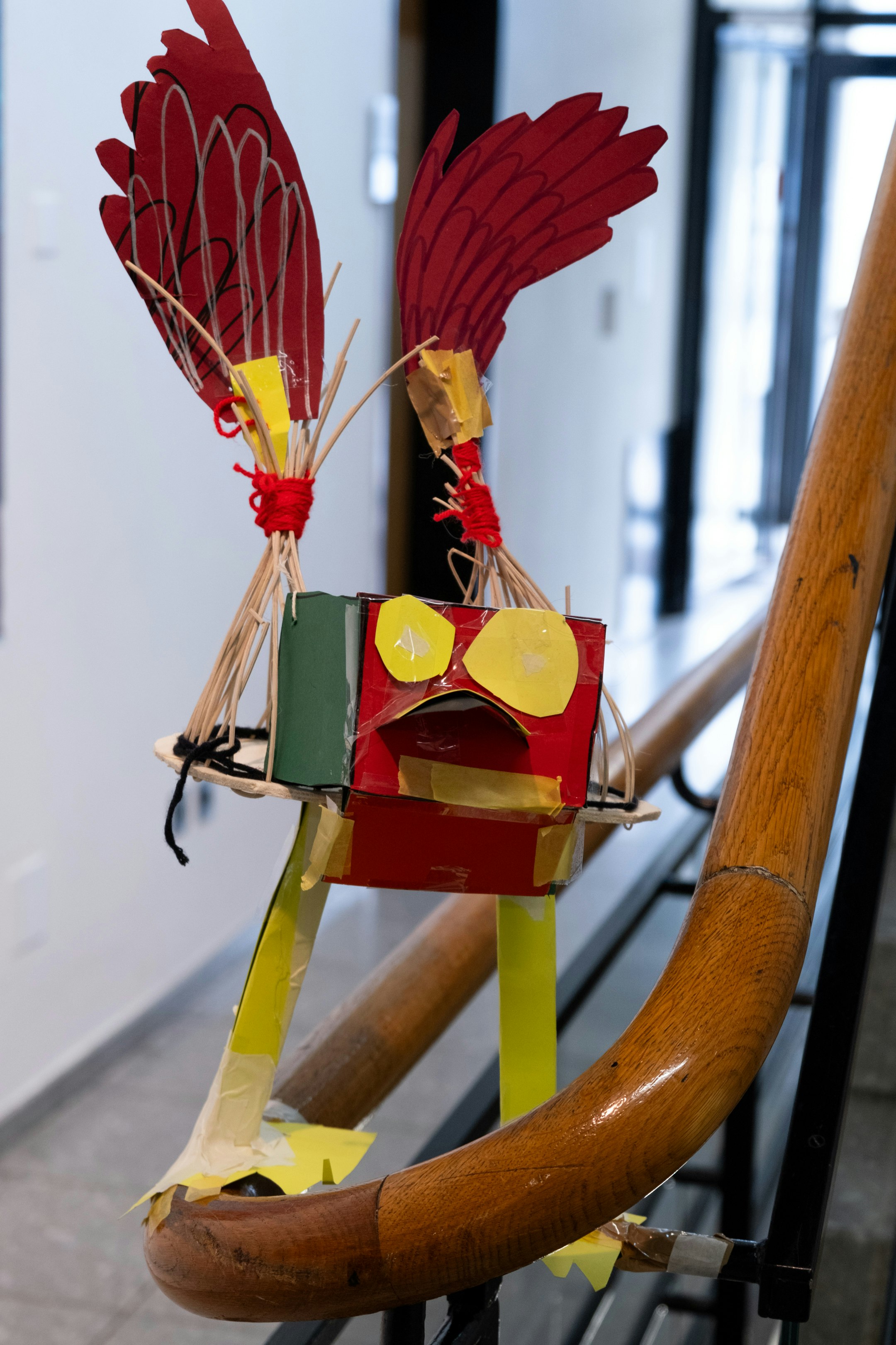 Ein Monster, das von einem Kind aus Papier, Klebeband, Weidengeflecht und Holz gefertigt ist, ist auf einem Treppengeländer in einem Innenraum installiert.