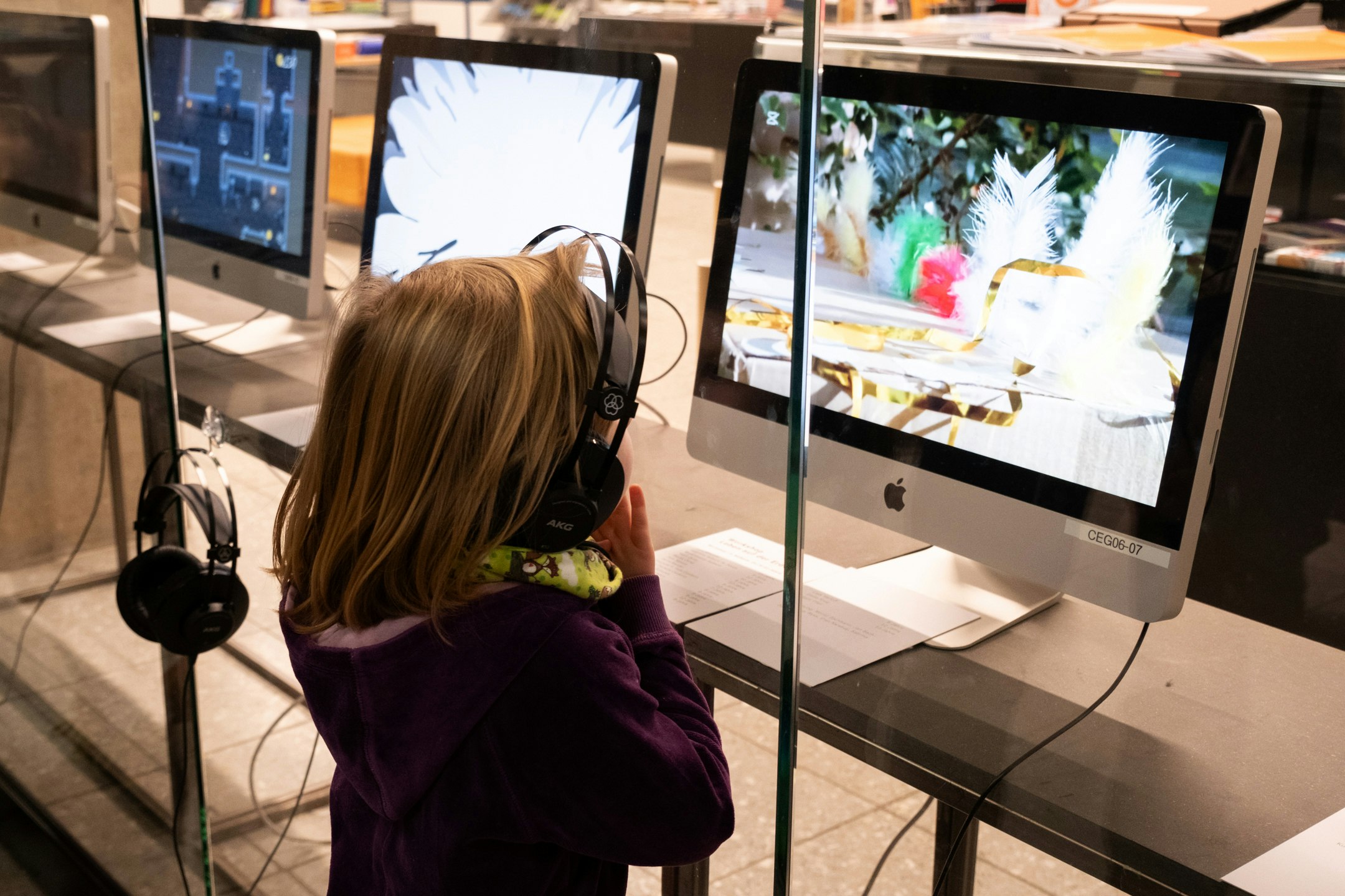 Ein Kind trägt Kopfhörer und schaut auf ein Bildschirm.