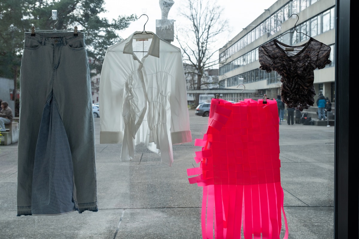 Von Kindern hergestellte Stoffobjekte und Kleidungsstücke sind an einer Fensterscheibe der Schule für Gestaltung Basel ausgestellt.