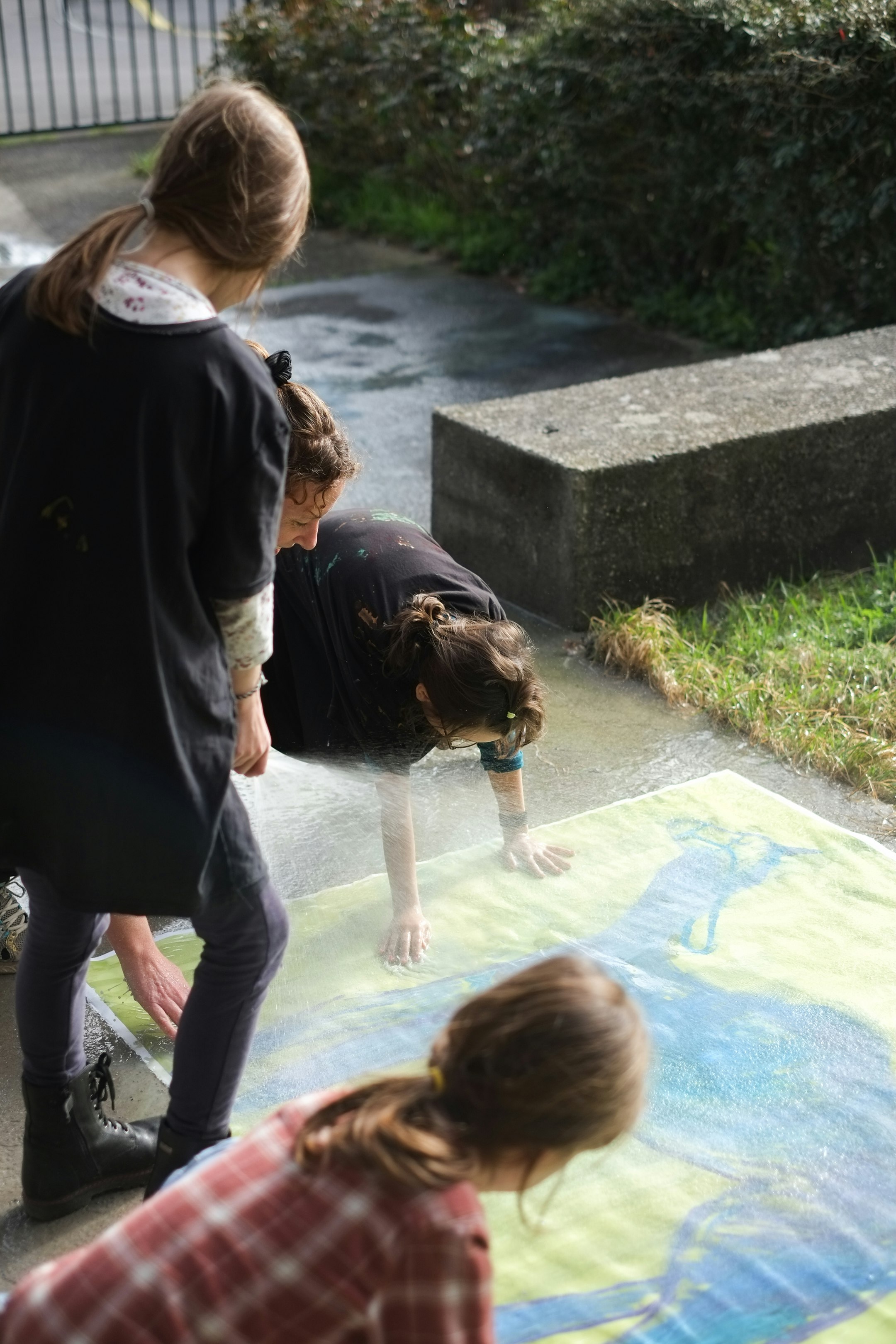 Kinder waschen ein gemaltes Bild mit Wasser ab