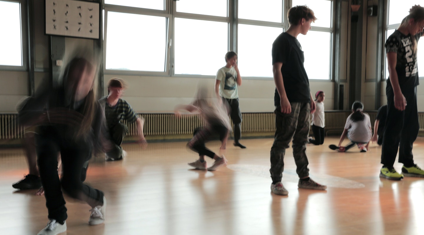 Kinder und Jugendliche tanzen in einem Raum.