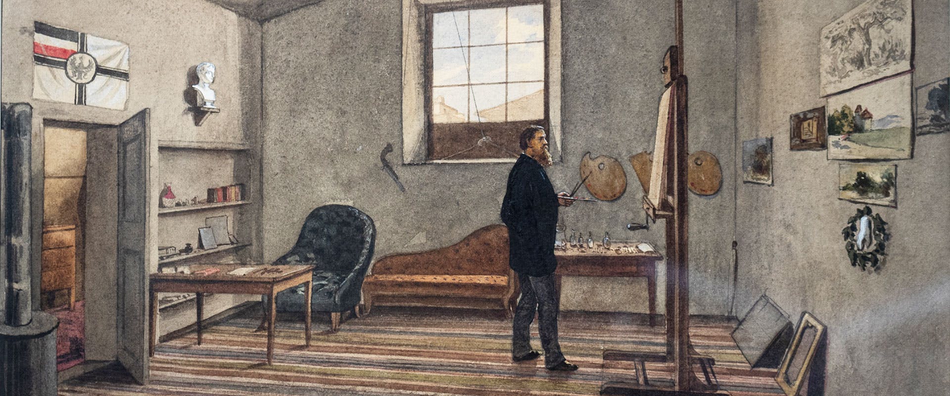 Un uomo sta in piedi in uno studio d'arte ben illuminato, con pareti decorate da dipinti, accanto a un cavalletto con tavolozza e pennelli in mano.