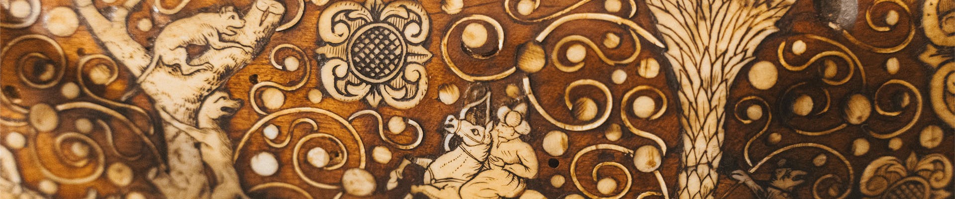 Una decorazione intagliata su legno mostra intricati motivi floreali e animali, caratterizzata da dettagli raffinati e colori terrosi, evidenziando l'artigianato artistico tradizionale.