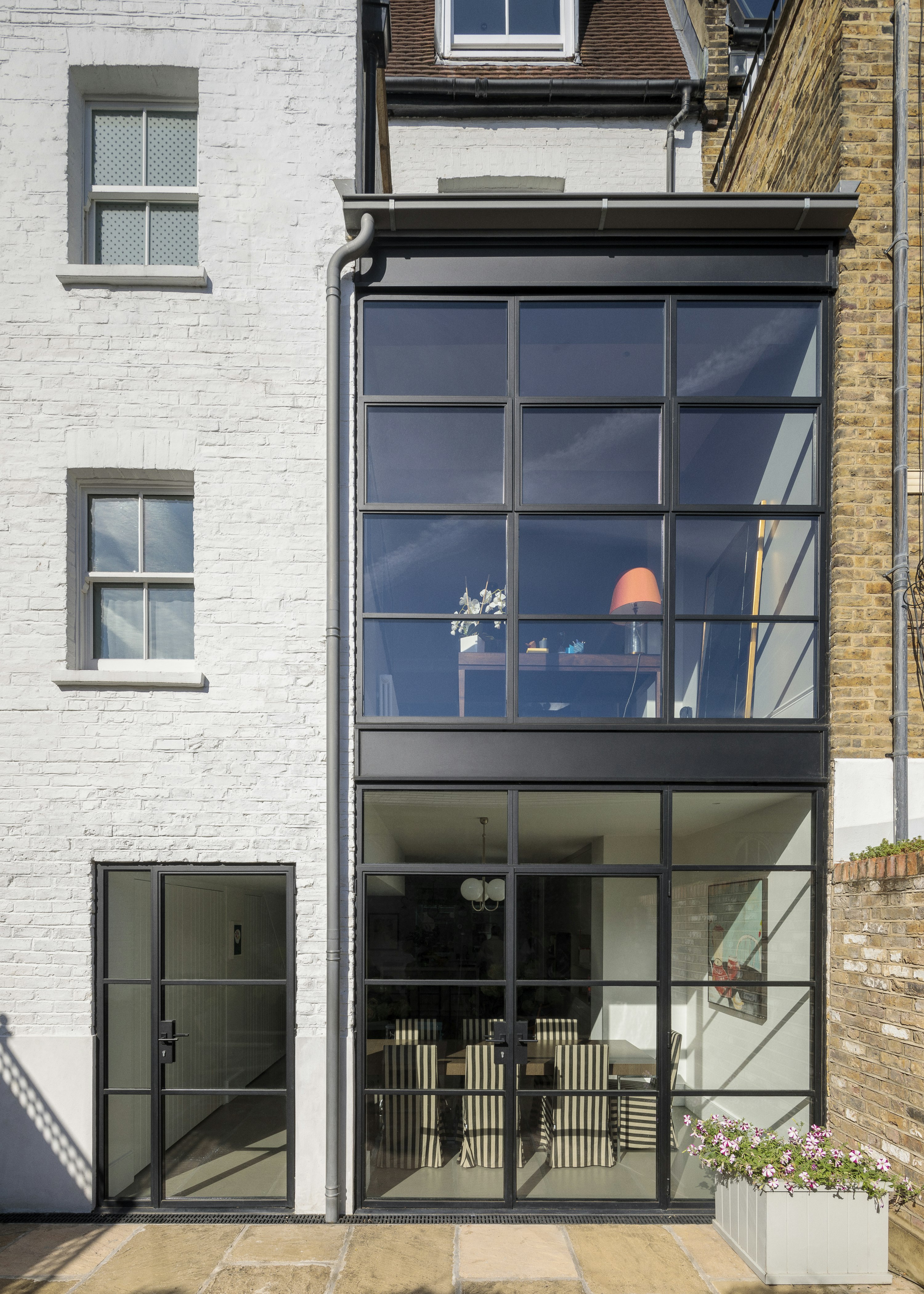 Looking into a two-storey, glazed rear extension, with a dining room on the ground floor and a home office on the first floor.