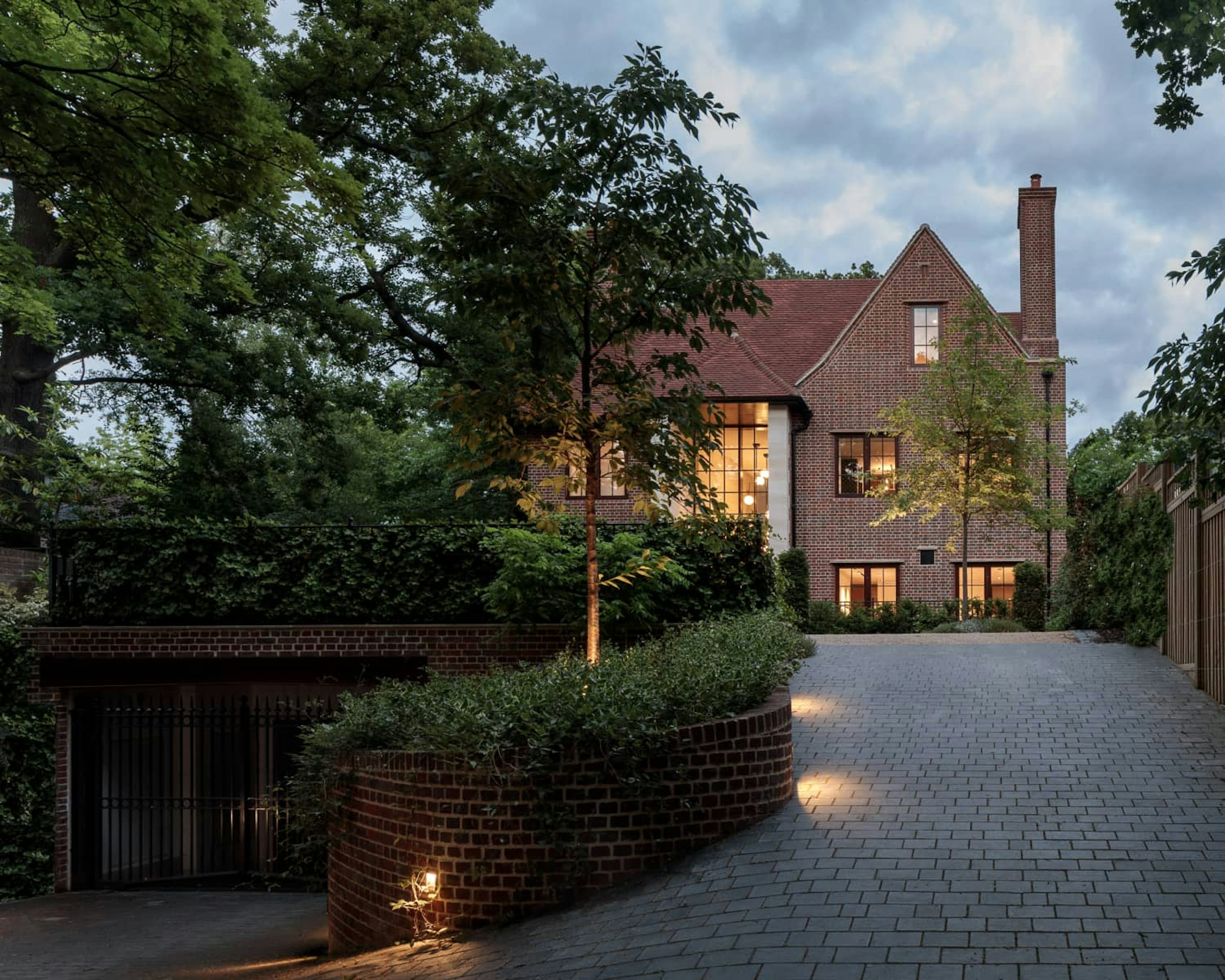 New-build Arts and Crafts style house built from red brick with gabled roof and crittall bay window and underground parking.