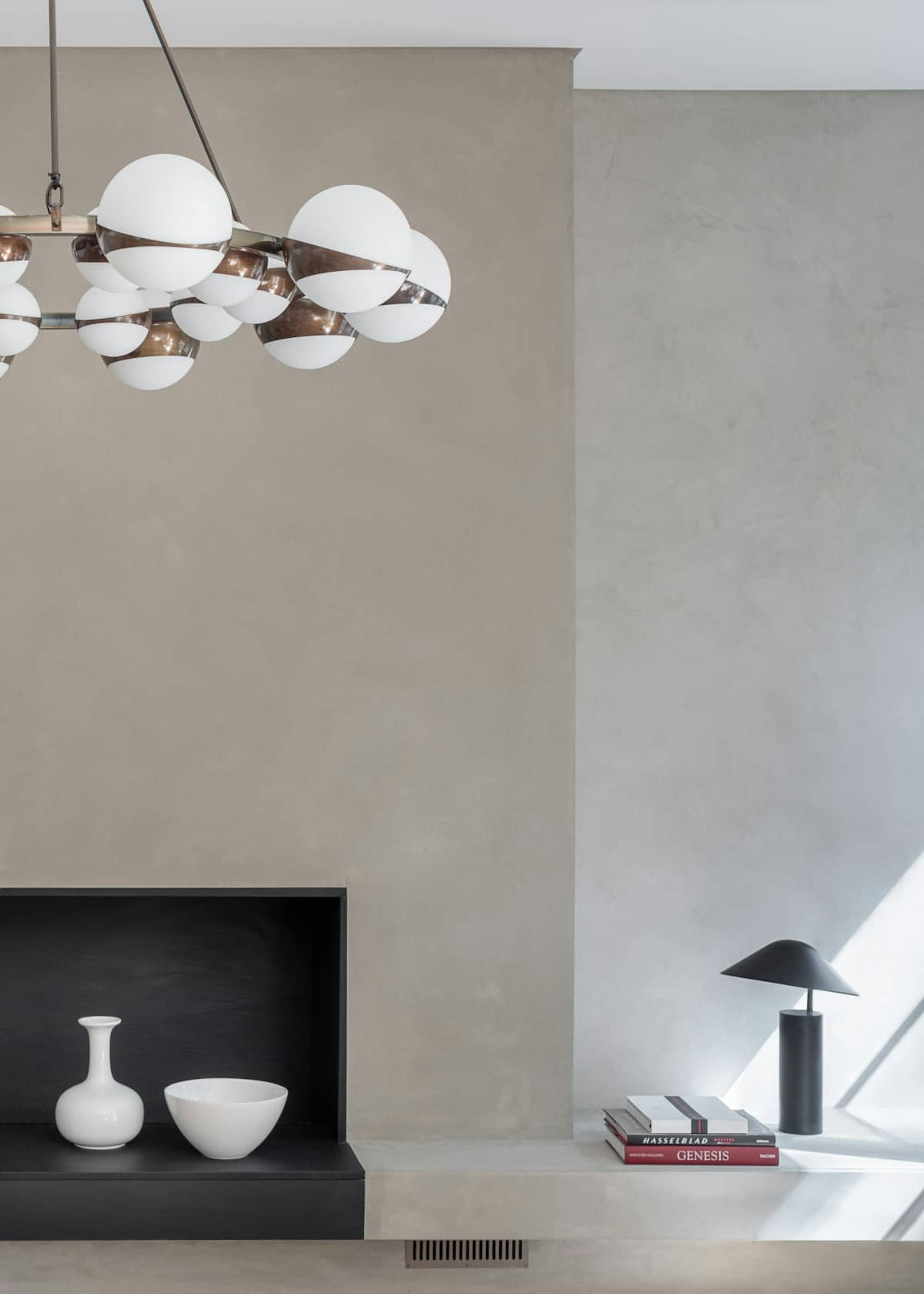 Mid-century inspired chandelier hangs in a minimalist living room with pale stone walls and contemporary fireplace.