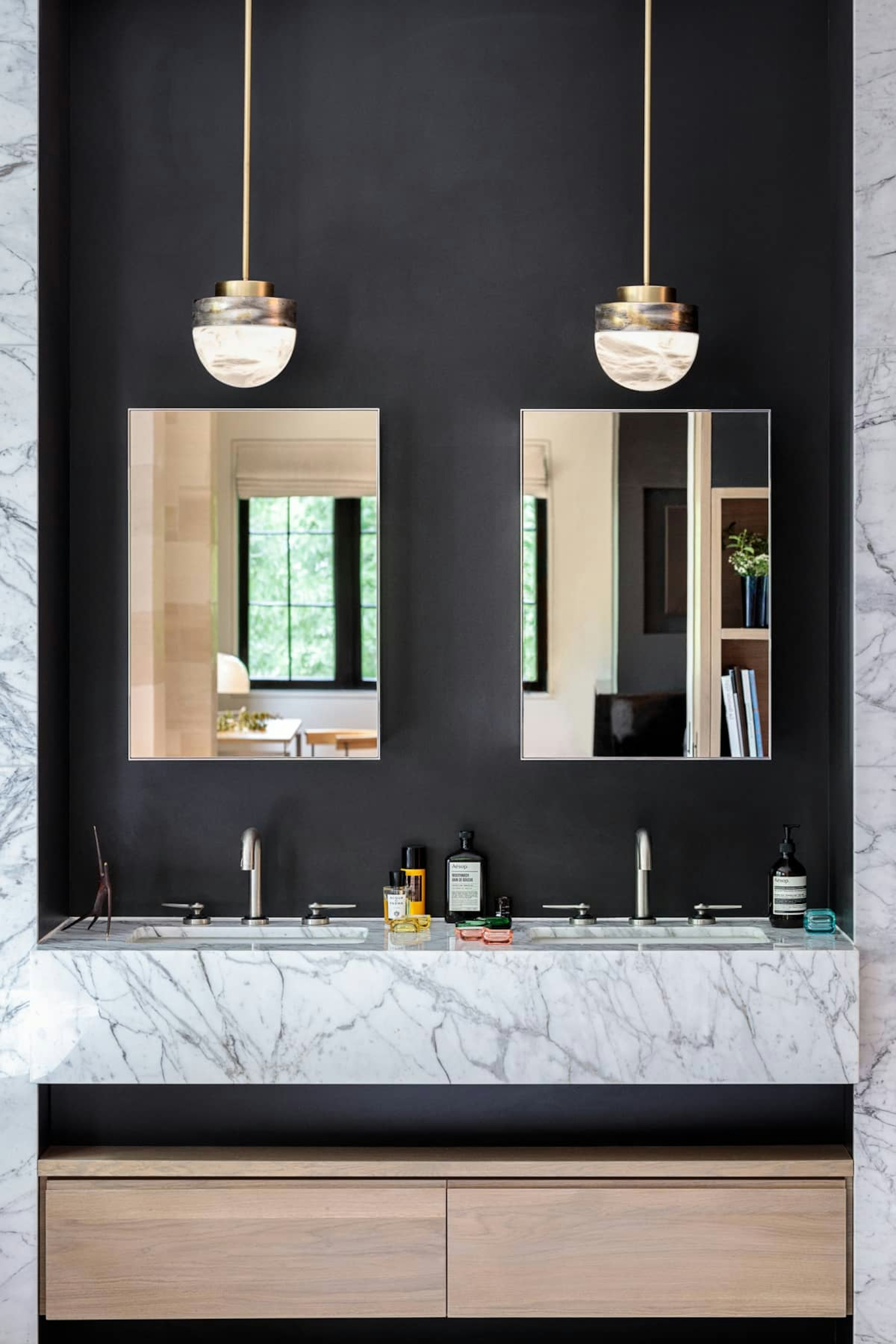 Double vanity in the master bathroom with a marble countertop and art deco style light fixtures above symmetrical mirrors.