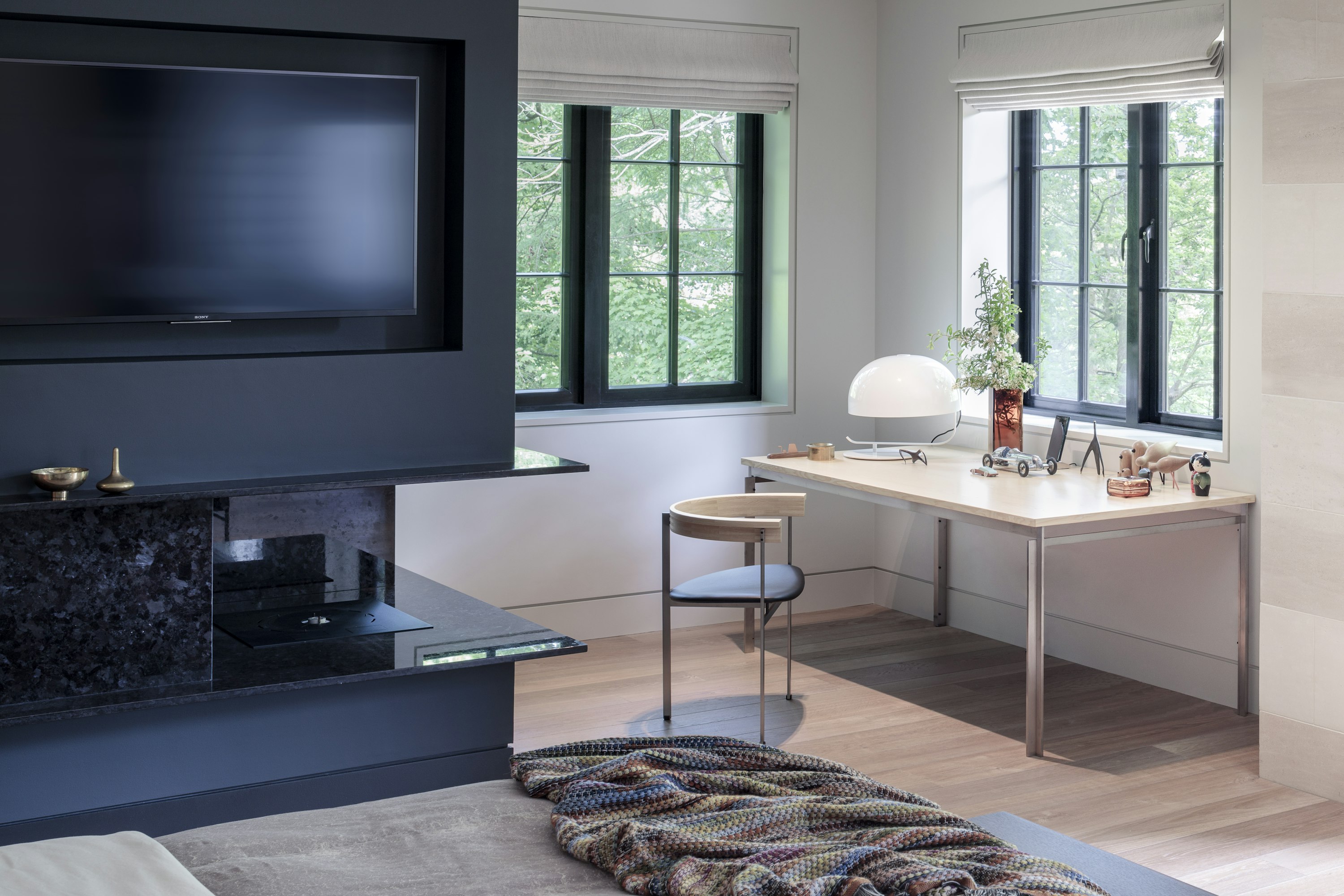 Luxury interior design for a master bedroom with mid-century furniture and a floating, black granite fireplace surround.