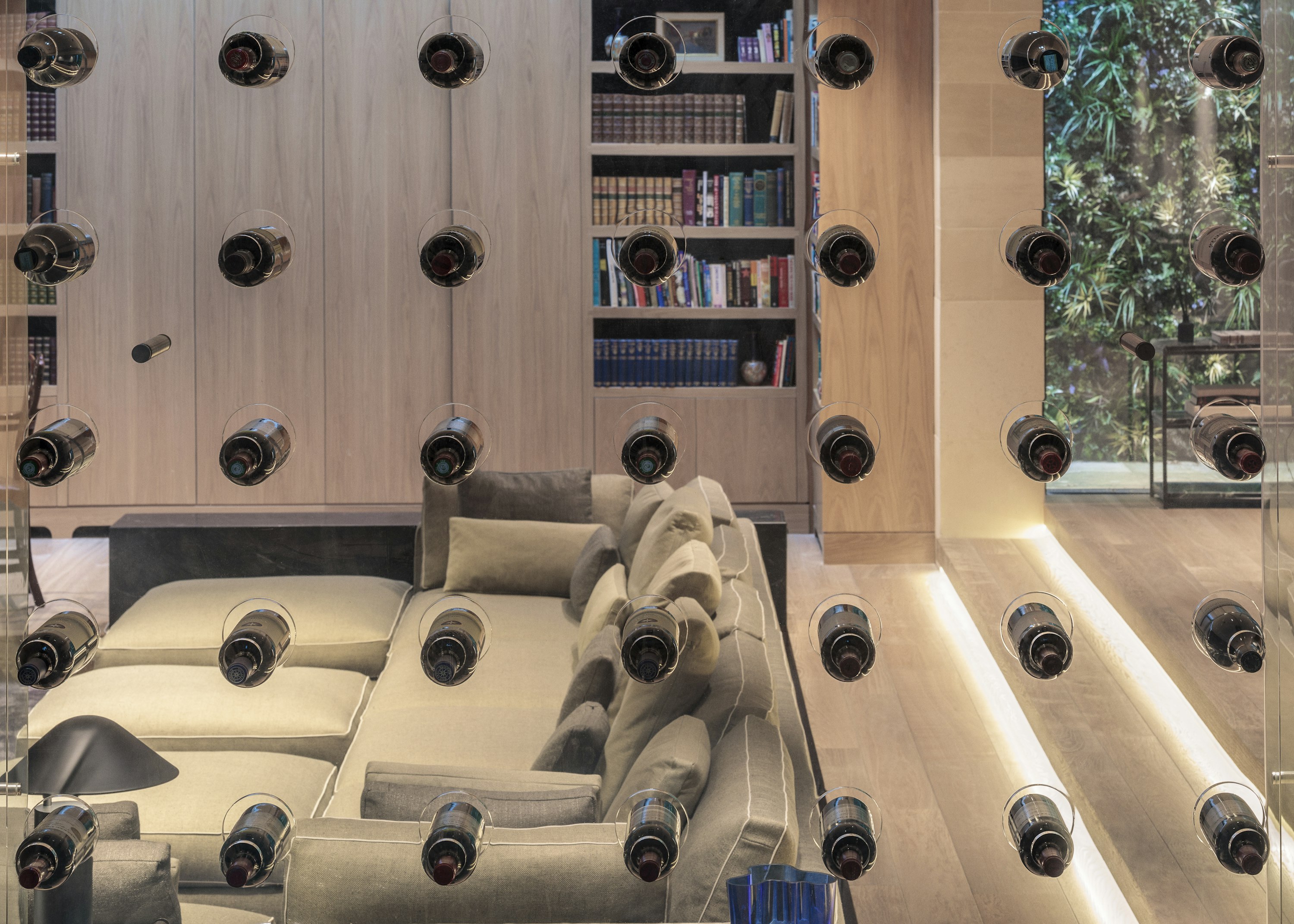 A custom-designed, contemporary wine rack, where wine bottles are balanced in extruded, cylindrical inserts in a glass dividing wall.
