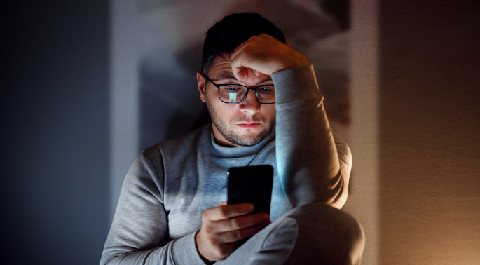 Person in dark room looking at cellphone.