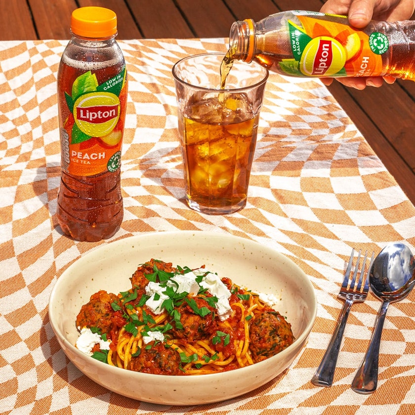 Lipton Peach Ice Tea on a table with some spaghetti