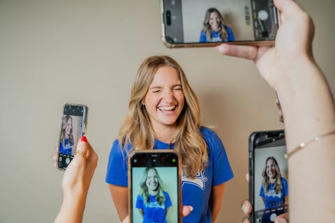 Woman being photographed by four smart phones