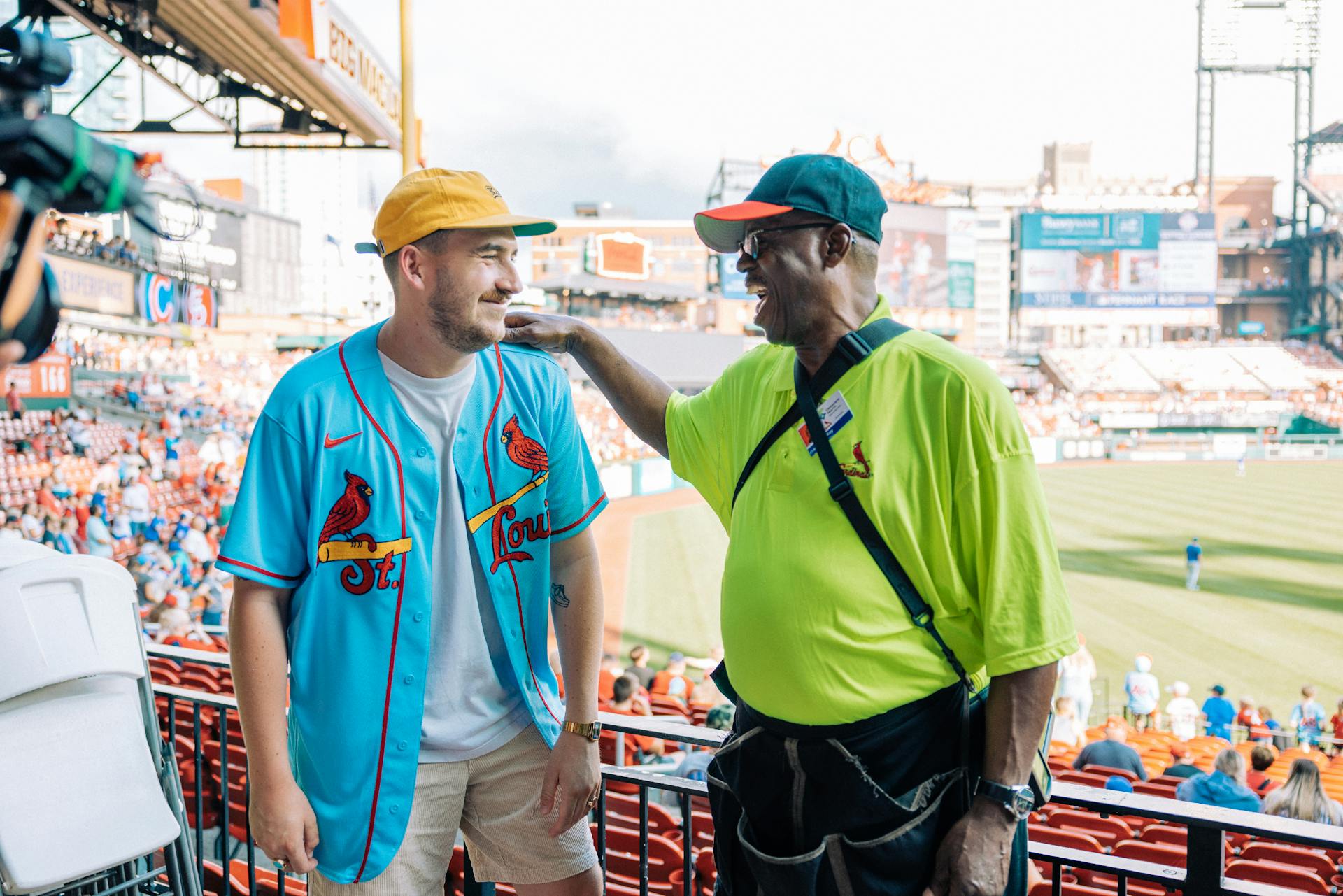 two men talking in a baseball stadium while filmed