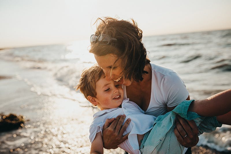 there is a woman holding a baby on the beach