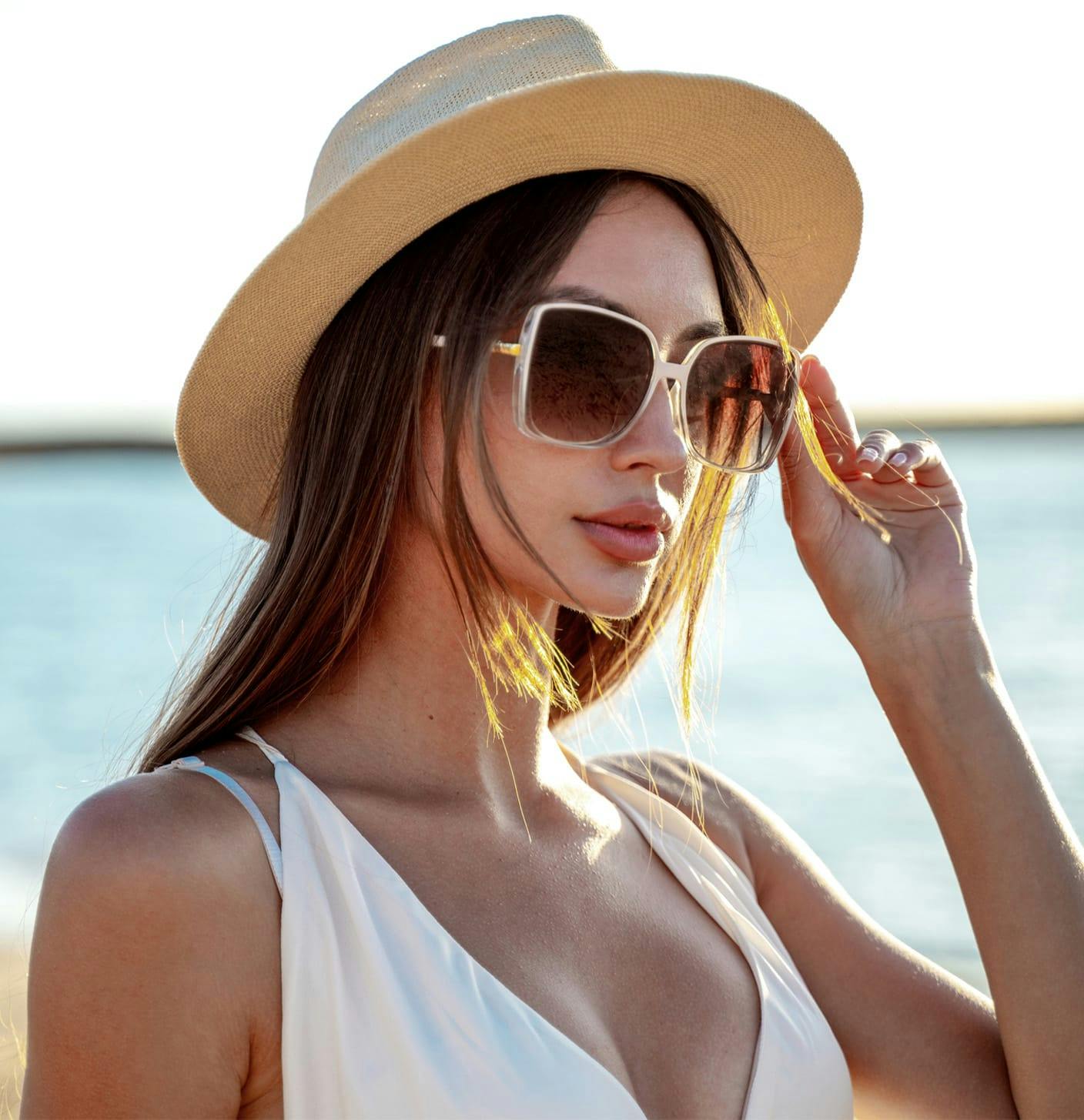 Woman in sunglasses and a sun hat on the beach