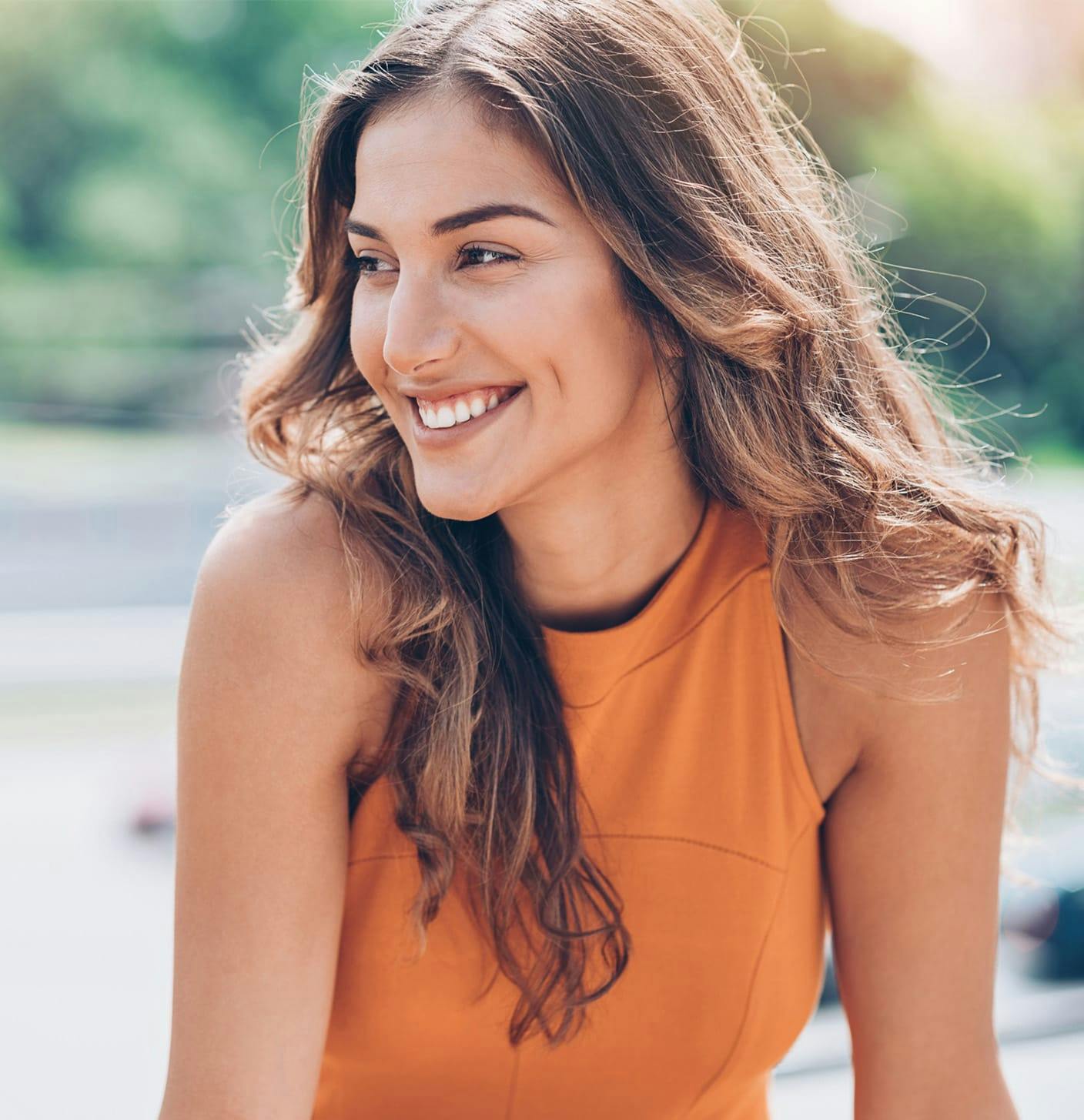 Woman in an orange top looking to the side