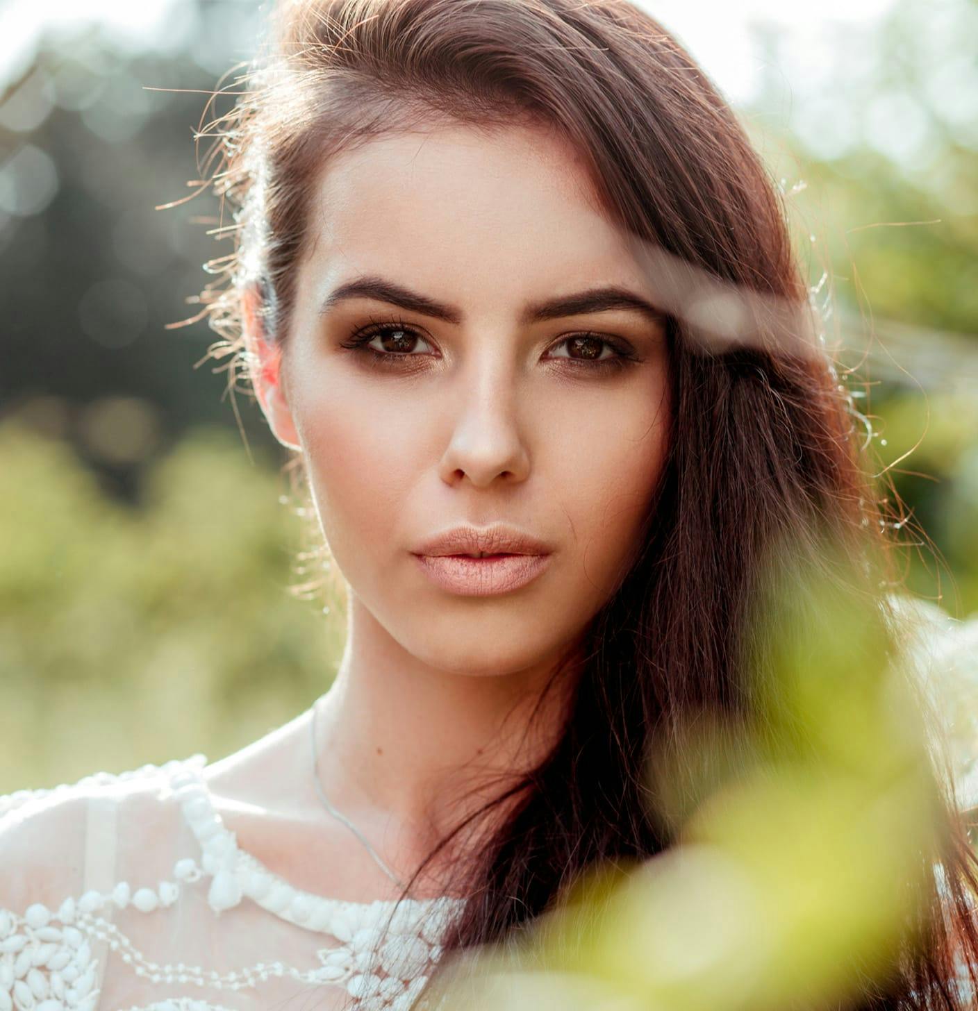 Woman behind some plants looking directly at the camera