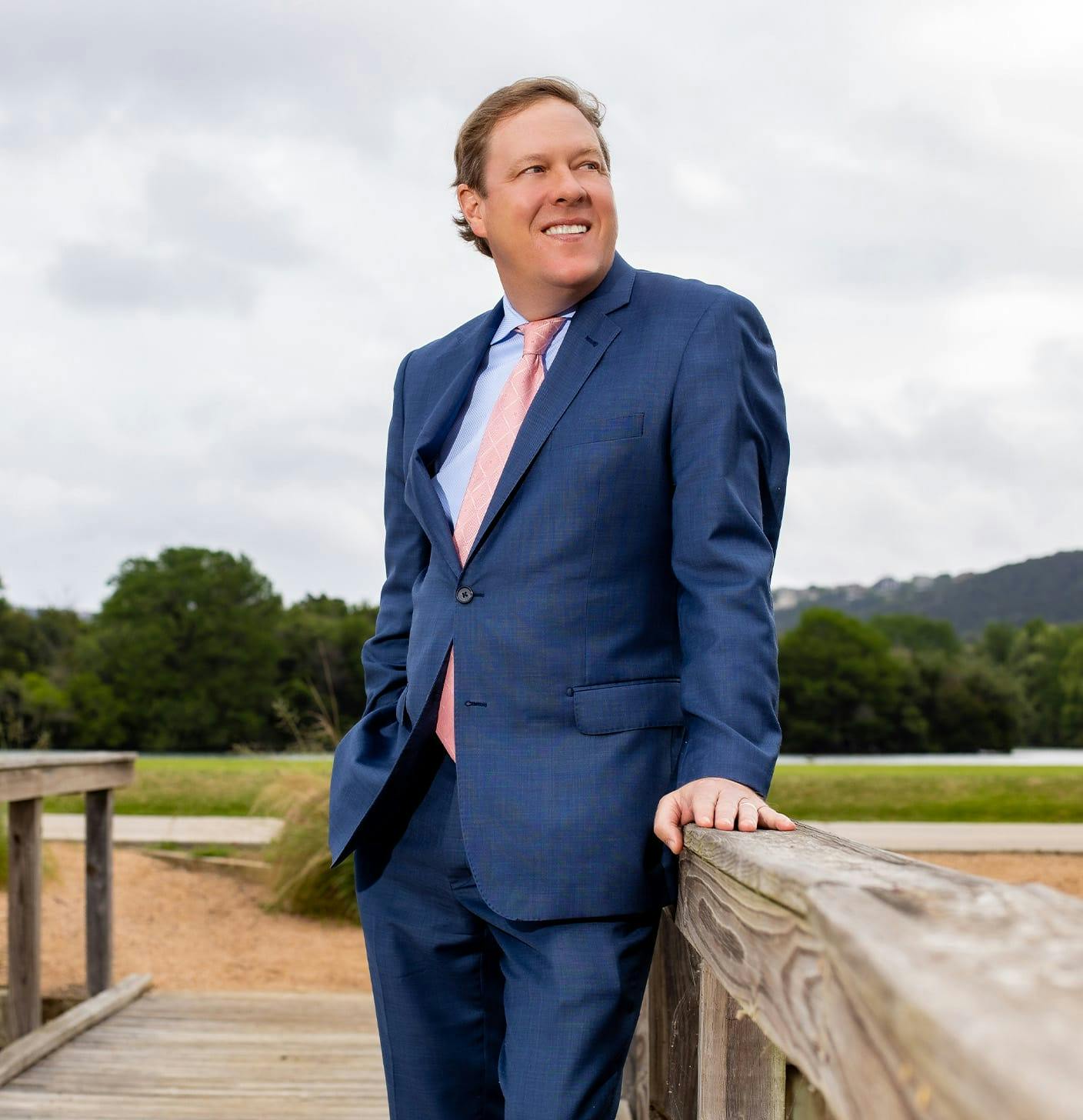 Dr. Haydon in a suit on a bridge, looking away