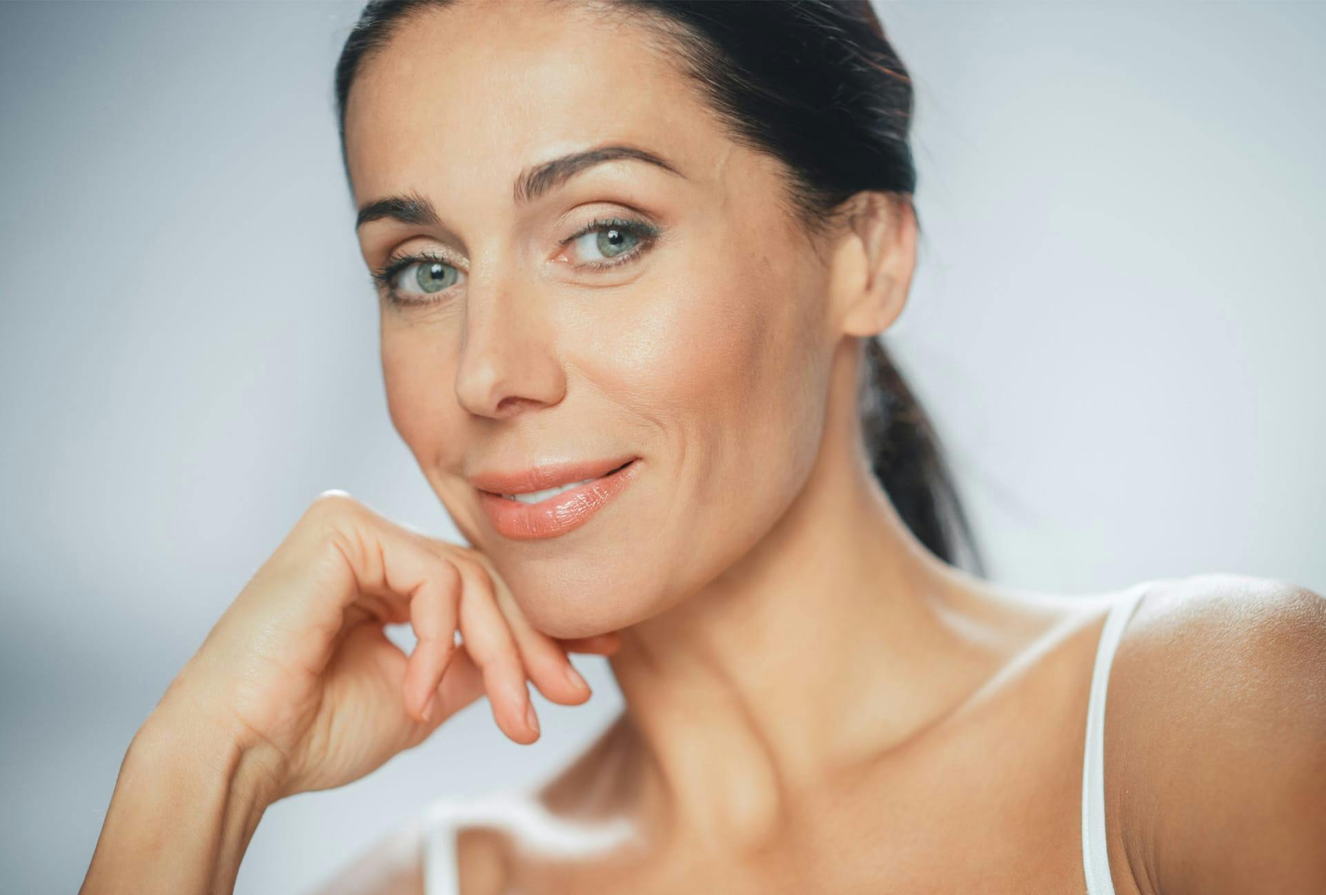 Woman with her hair back and hand against her chin, smiling