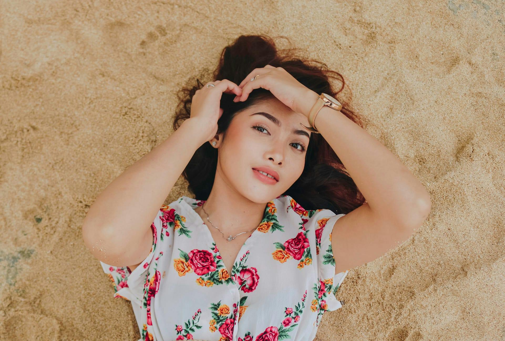Woman in a flowery top lying in the sand
