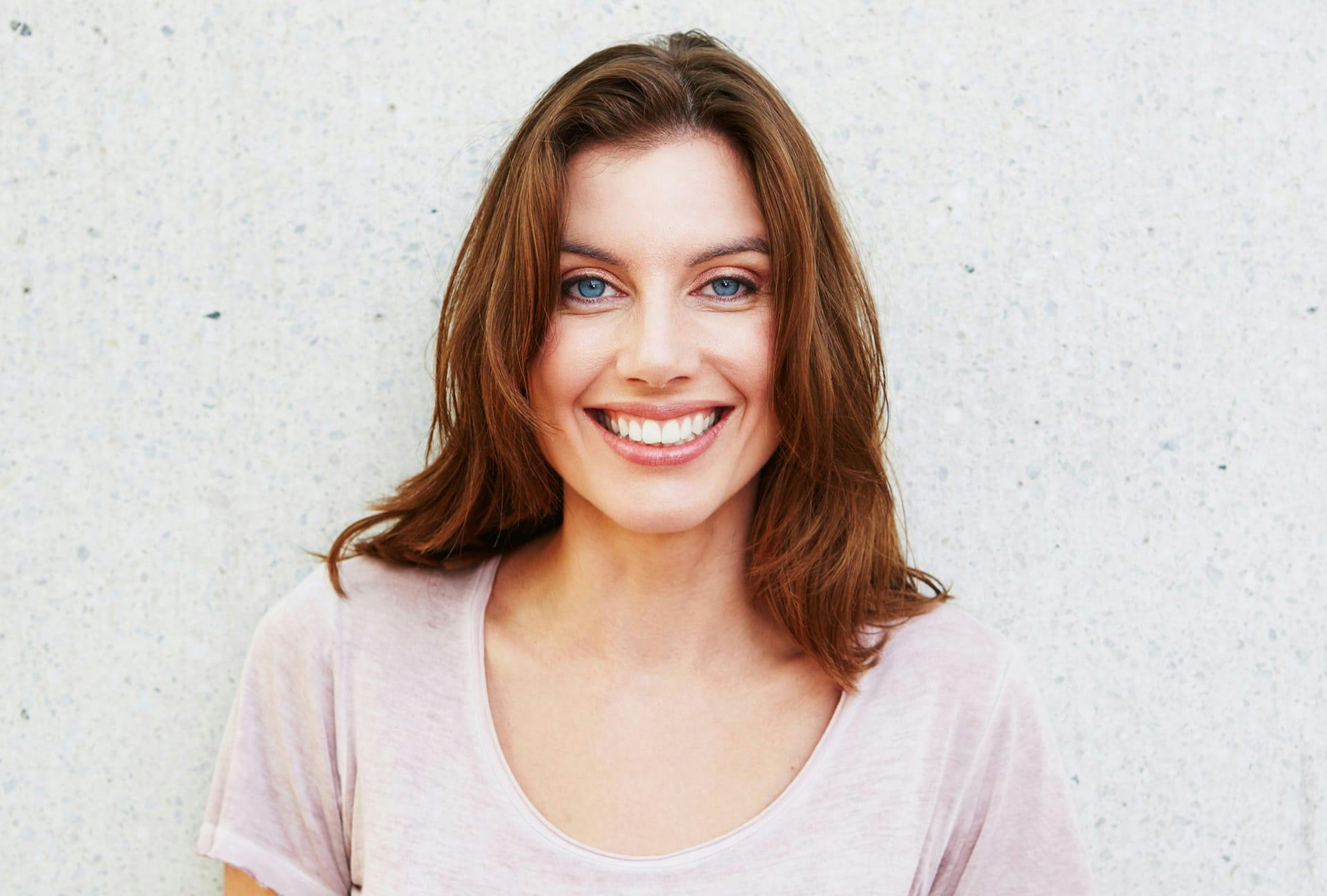 Woman standing against a wall and smiling