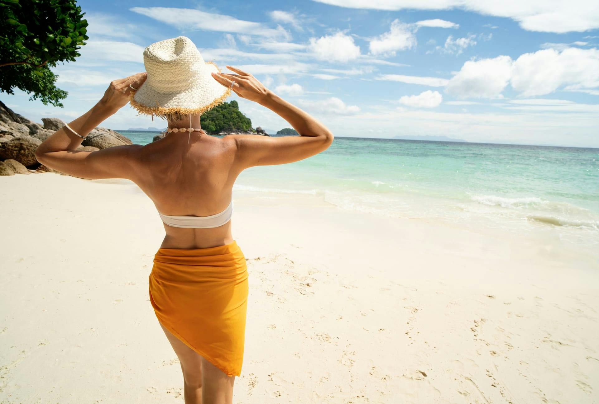 Woman in a sun hat on the beach, looking at the ocean