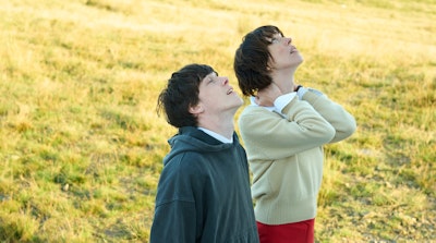 Man and woman stand in a field looking up at the sky