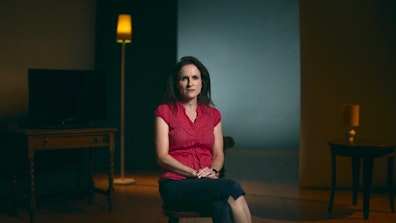 Woman pictured sitting on a chair in the middle of a dimly lit room