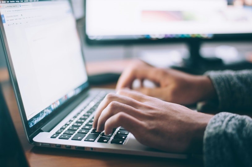 Photograph of hands resting on a laptop keyboard