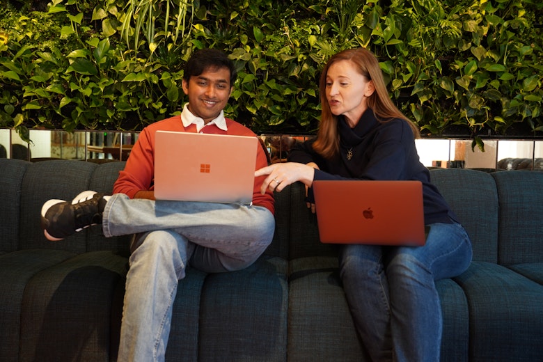 MarCloud team members working from laptops against a plant wall