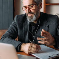 Man writing behind laptop