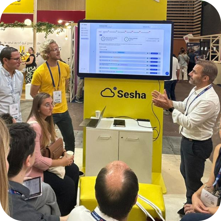 Équipe Sesha présentant la plateforme sur son stand lors du CNOEC, échange avec des visiteurs autour d'une démonstration produit