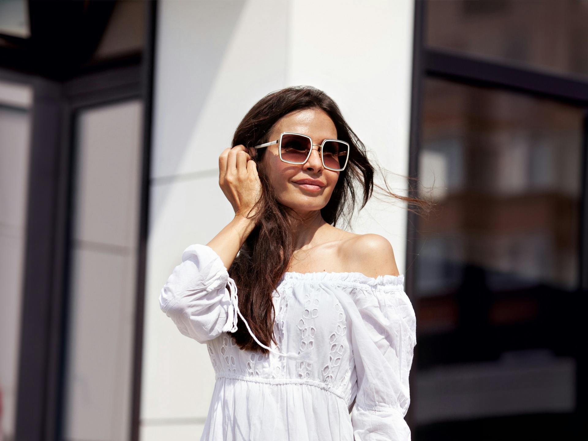Woman wearing white dress and sunglasses outside