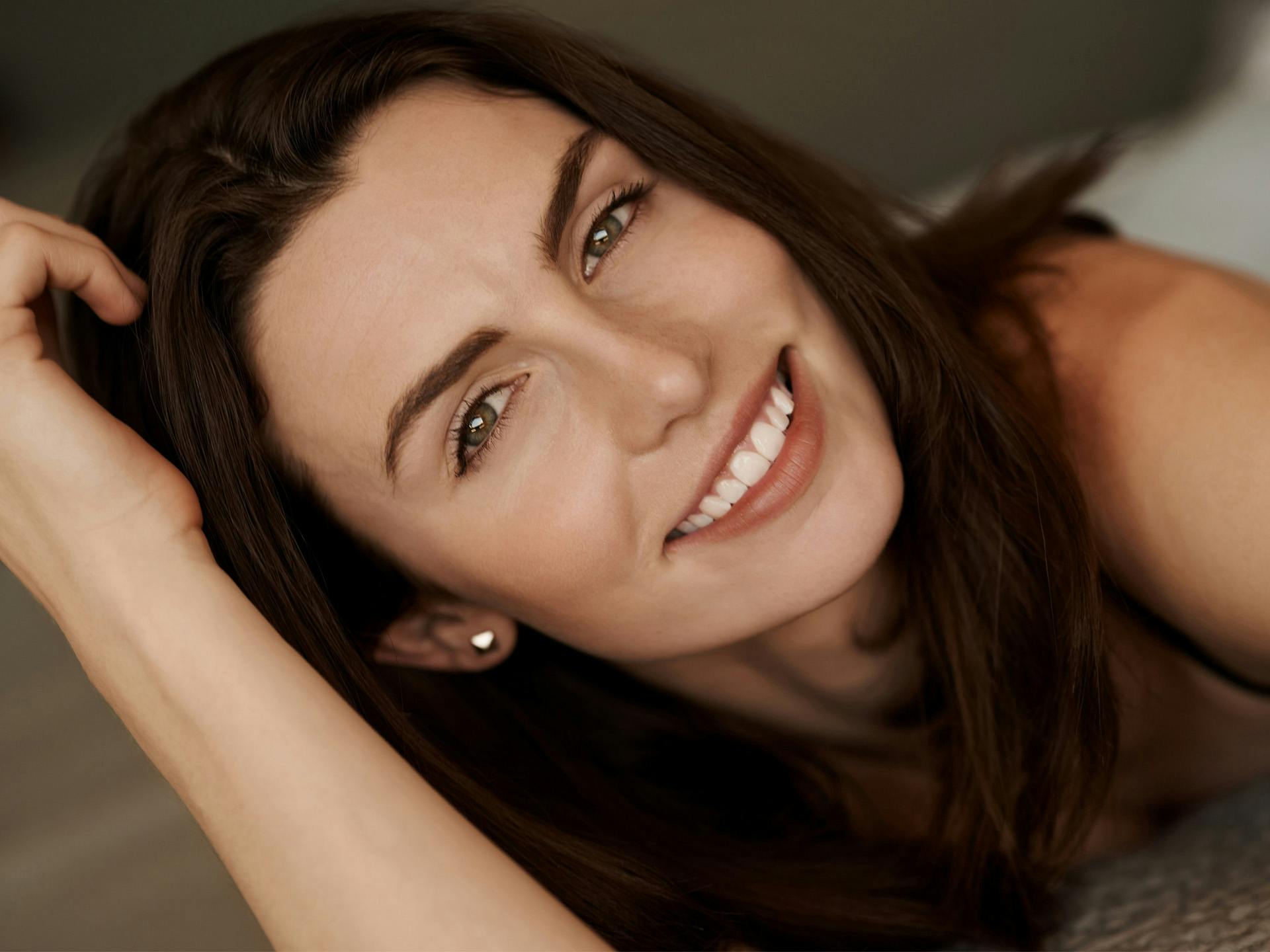 Brown haired woman laying down smiling