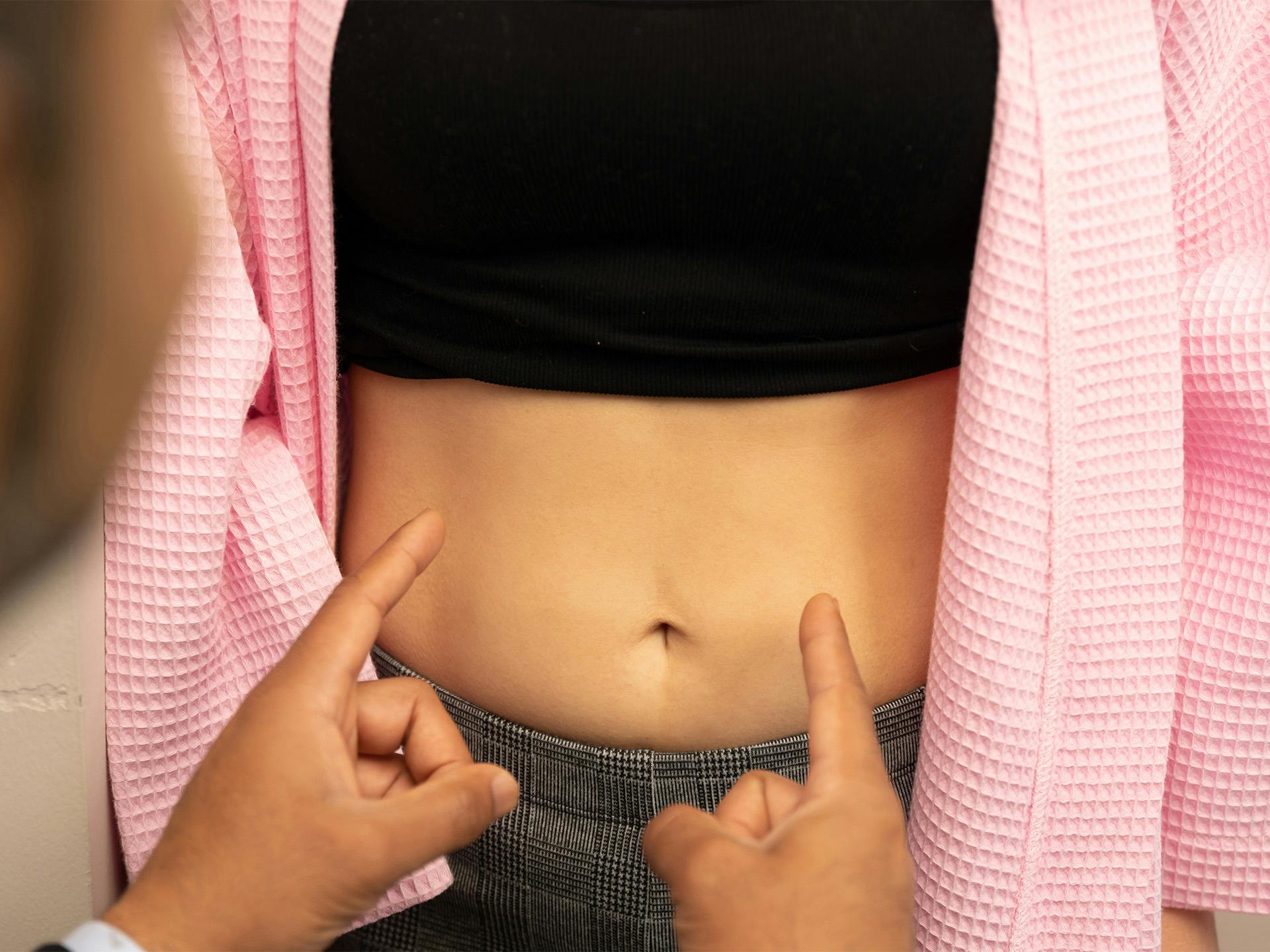 Woman having her stomach examined during consultation