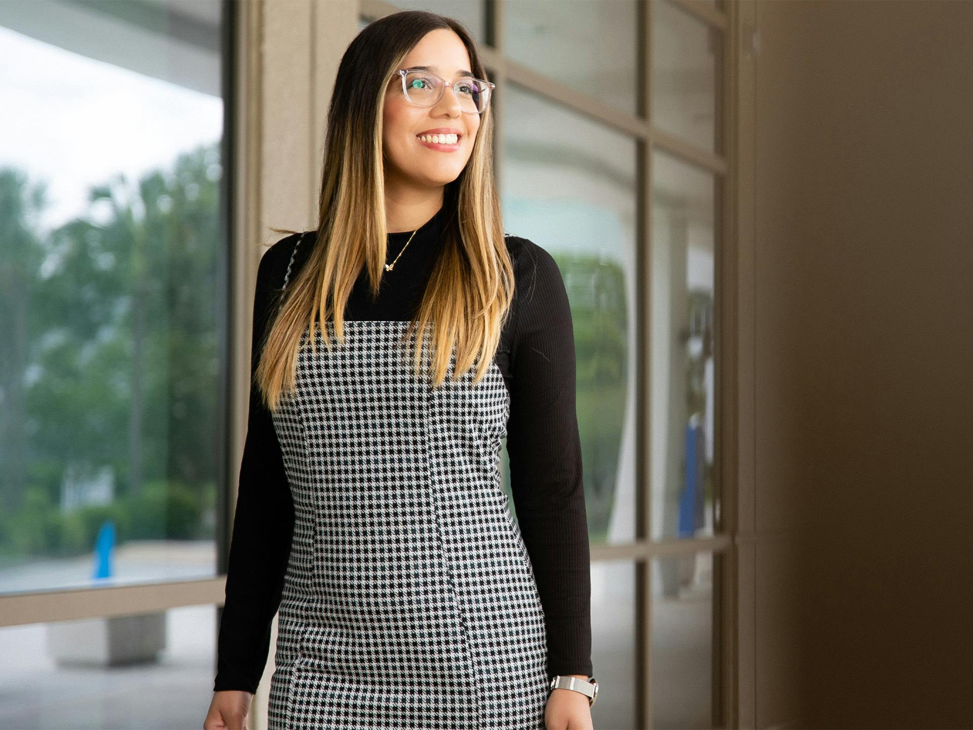 Woman wearing glasses and a plaid dress smiling outside