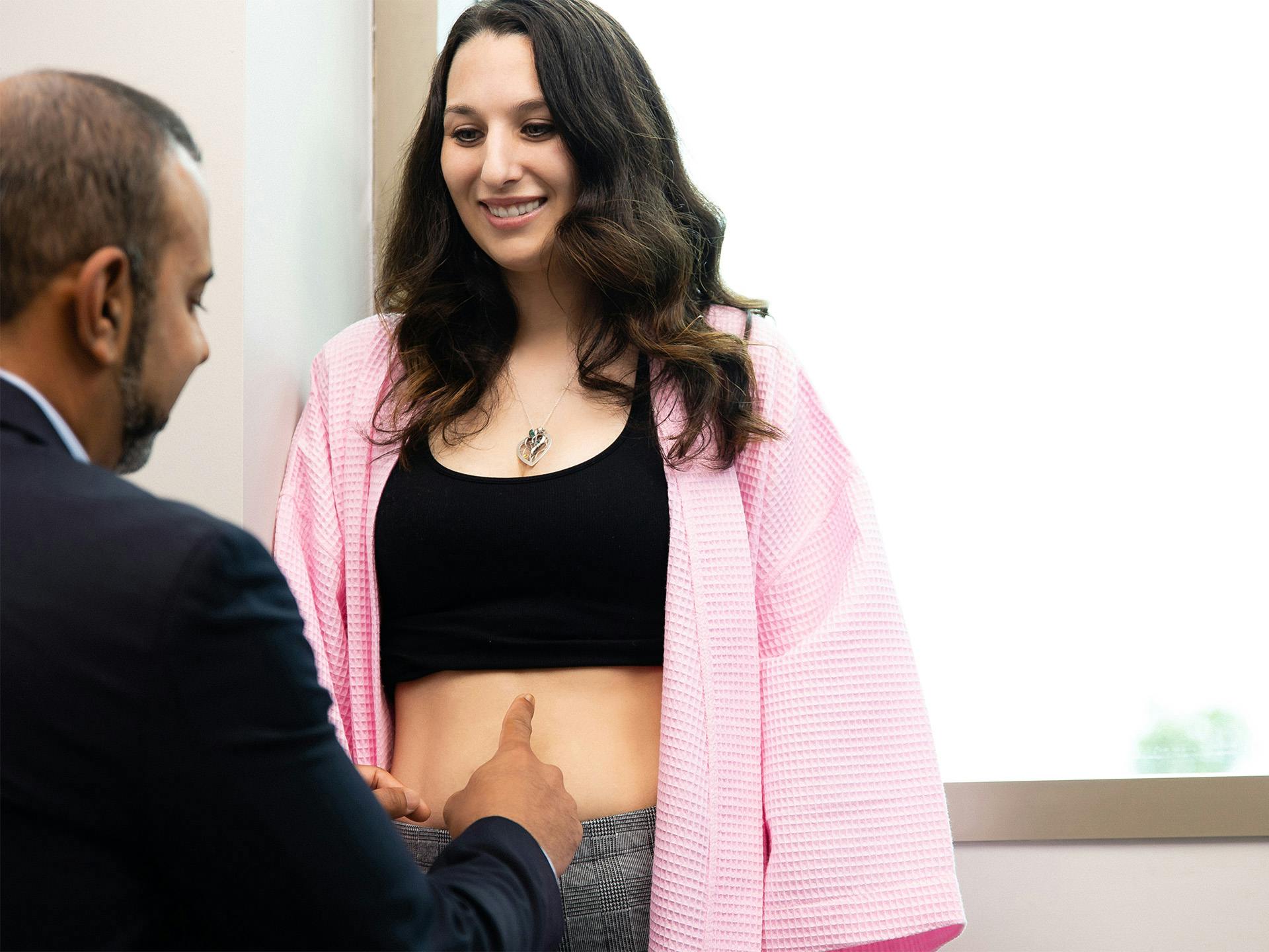 Woman having her stomach checked by doctor during consultation