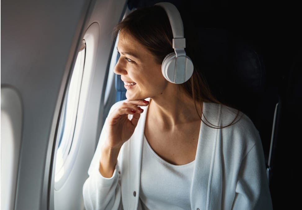 Smiling woman looking out the window of an airplane.