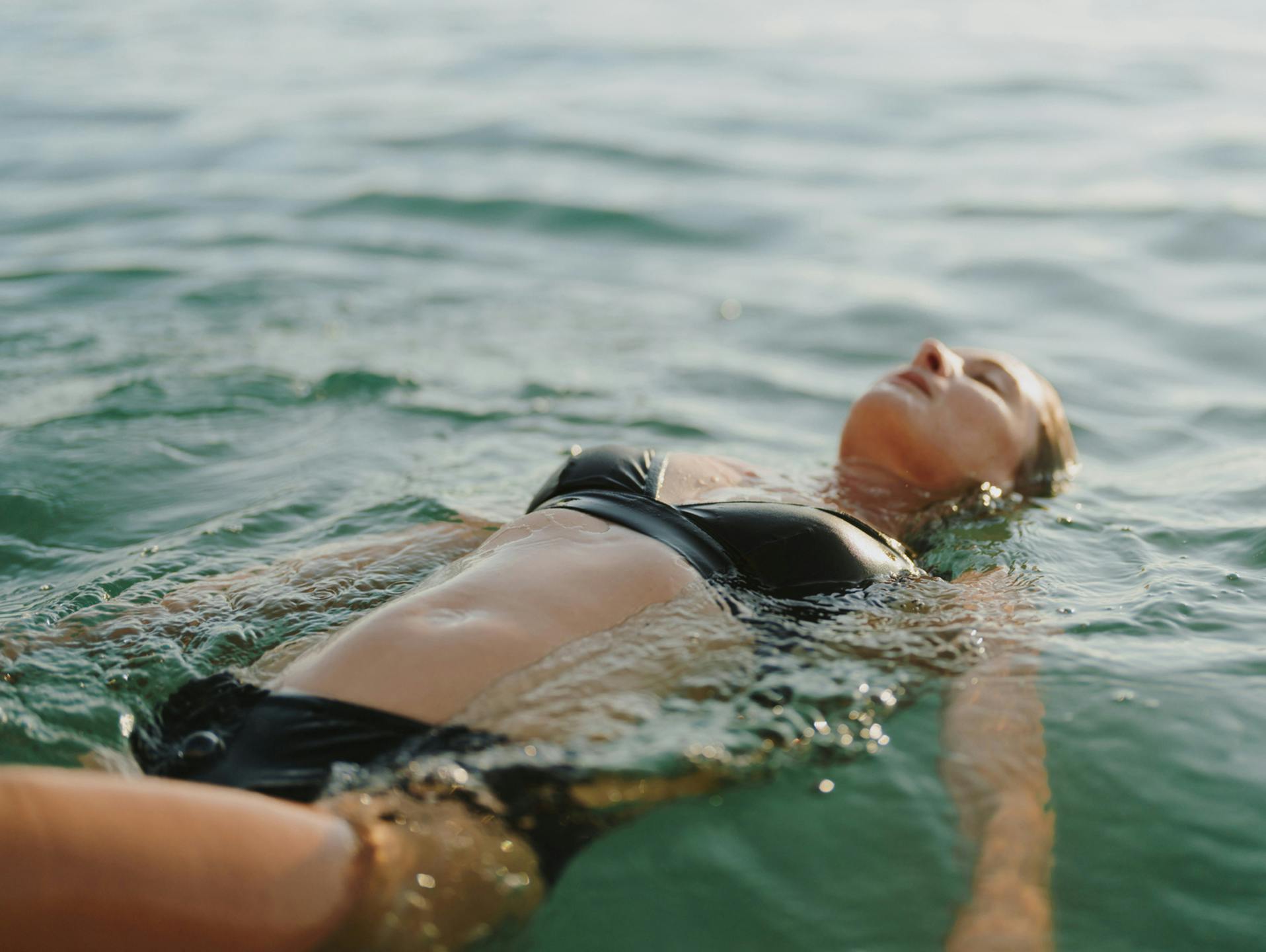 Woman in black bathing suit floating in water
