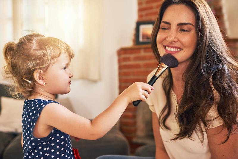 Little girl playing by pretending to add makeup to her moms face