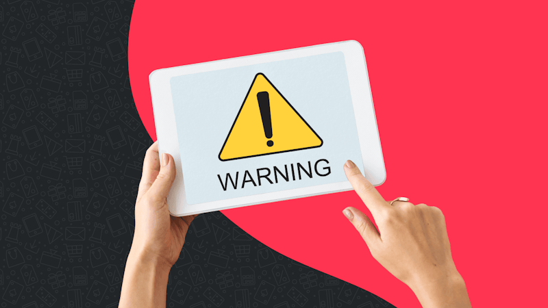 Alt text: A dundle red and black background with a white Ipad in the foreground showing a warning symbol