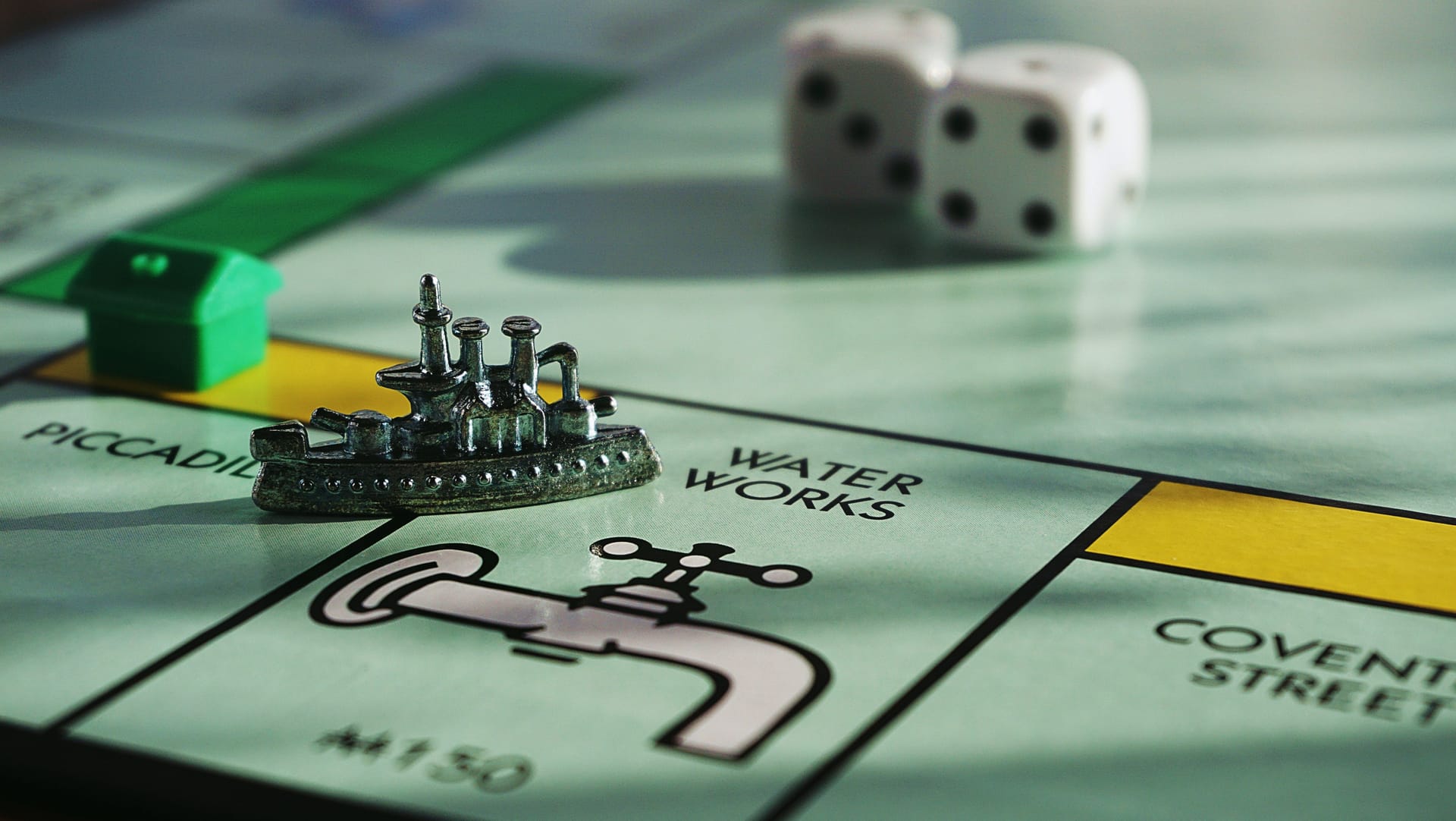 Close-up on the Monopoly board game, showing one field, a pawn and two cubes in the background.