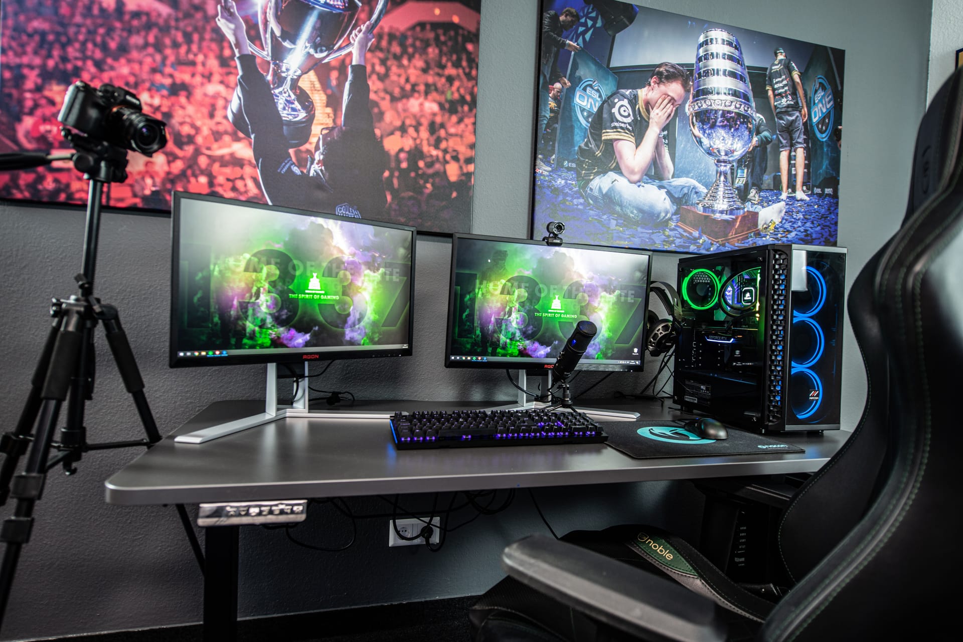 Streaming setup with a chair, computer, screens, camera and photos on the wall