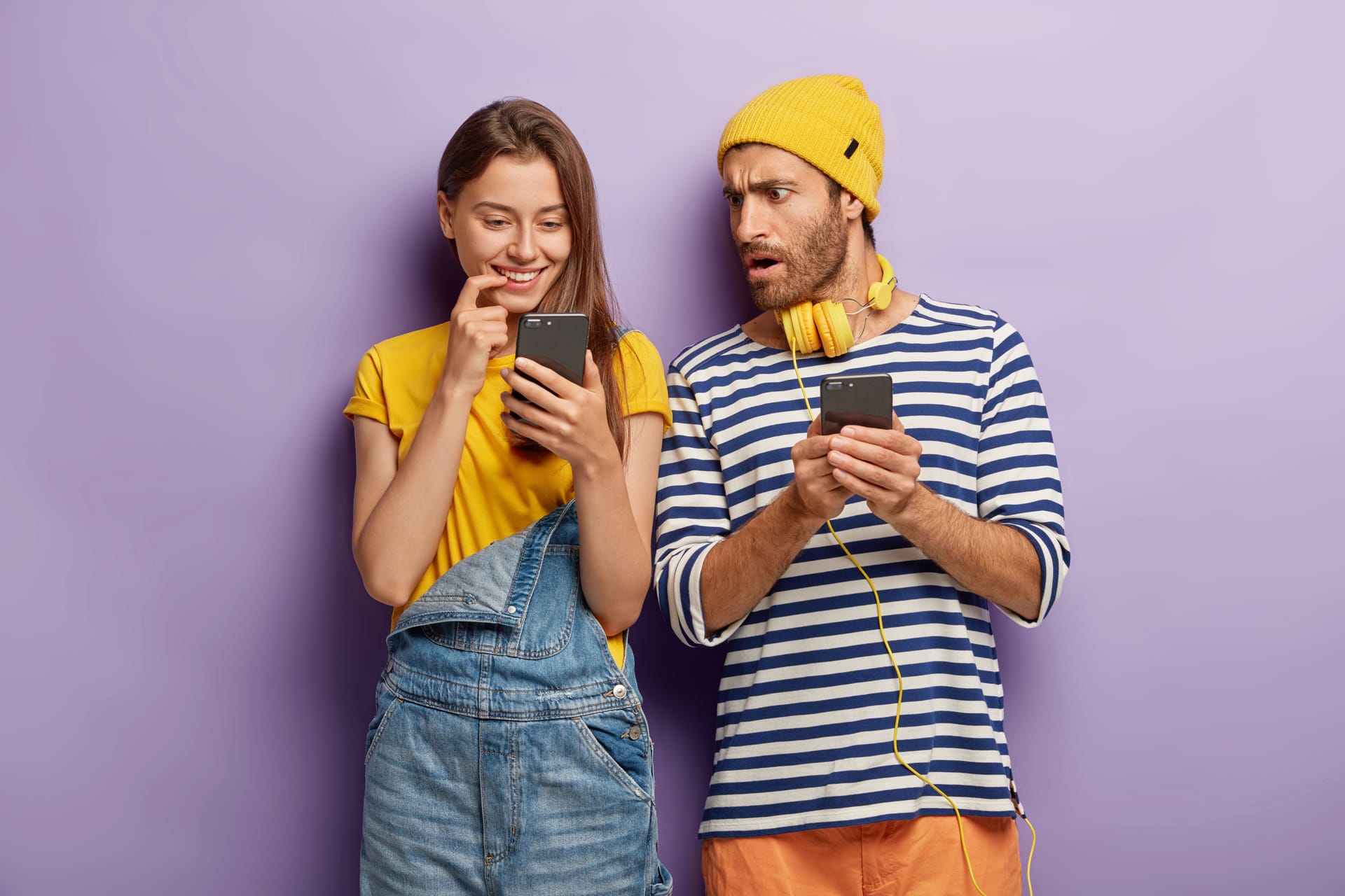 Young Gen-Z man and woman holding mobile phones.